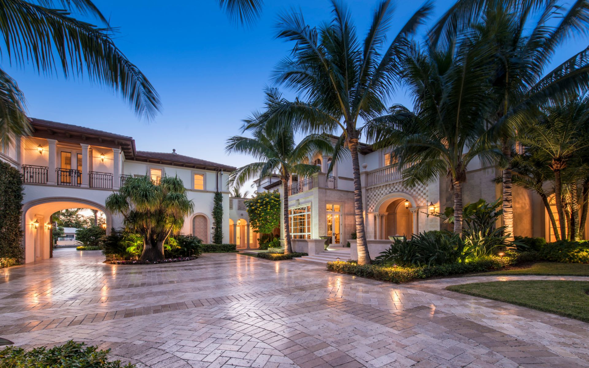 A view of a large mansion in Fort Lauderdale with palm trees and a driveway