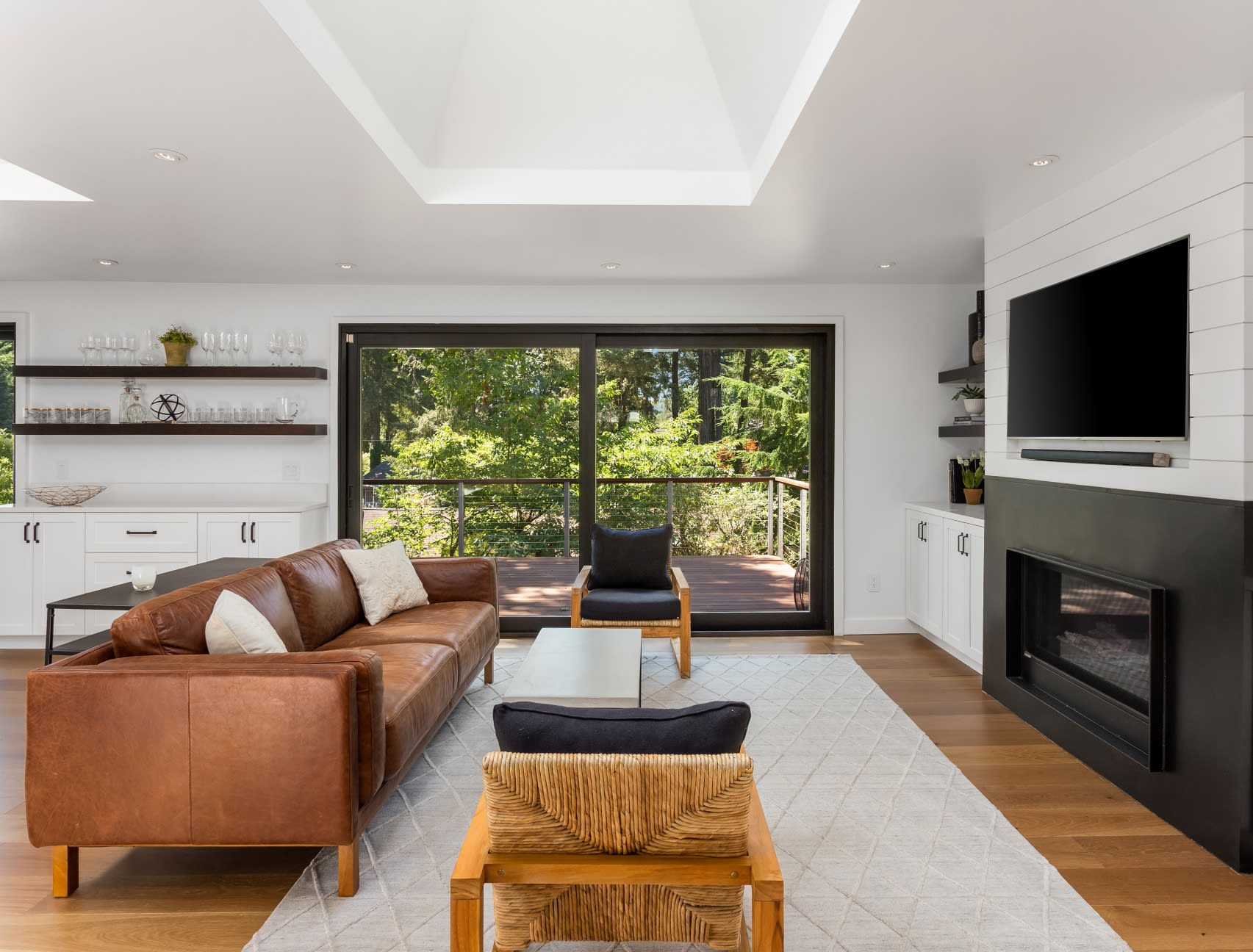 A living room with a brown leather couch, two armchairs, and a fireplace