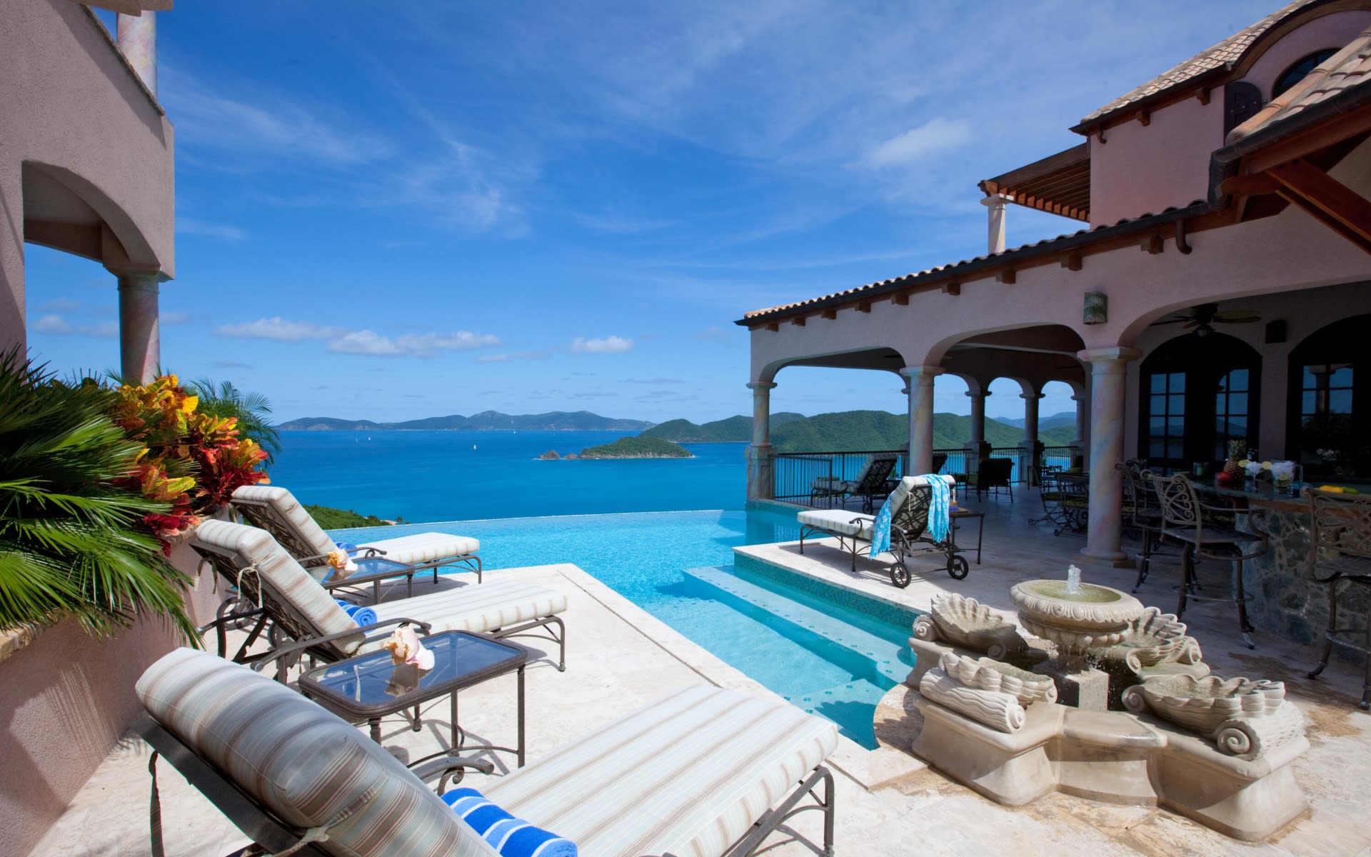 A luxurious private villa with a swimming pool and infinity edge, overlooking a turquoise ocean and a tropical beach