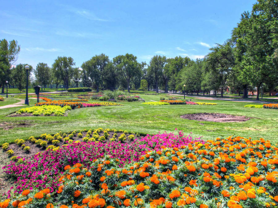 Vibrant community park near residential estates, with colorful flower beds and lush greenery.