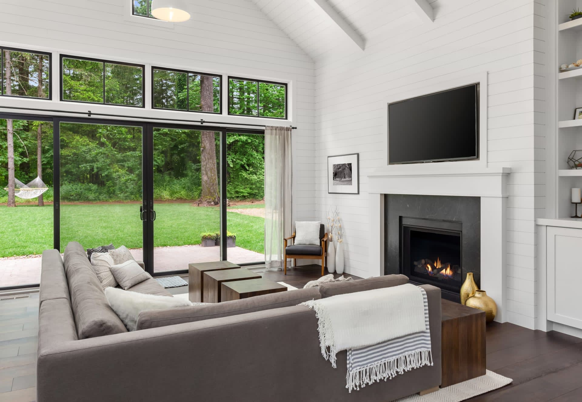 A cozy living room with a fireplace, comfortable couches, a coffee table, a television, and a sliding glass door to a patio.