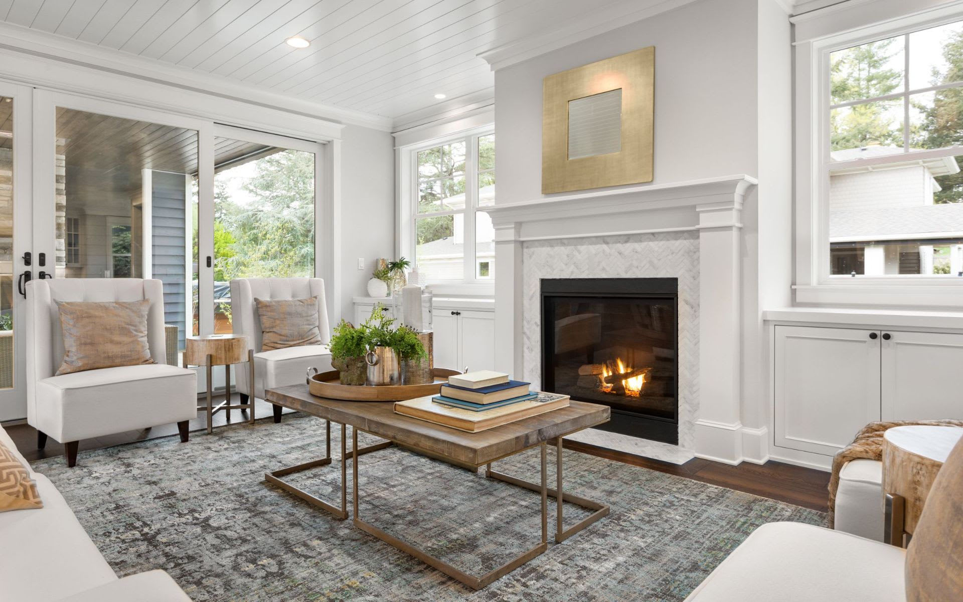 A cozy living room with a fireplace, coffee table, armchairs, and a rug