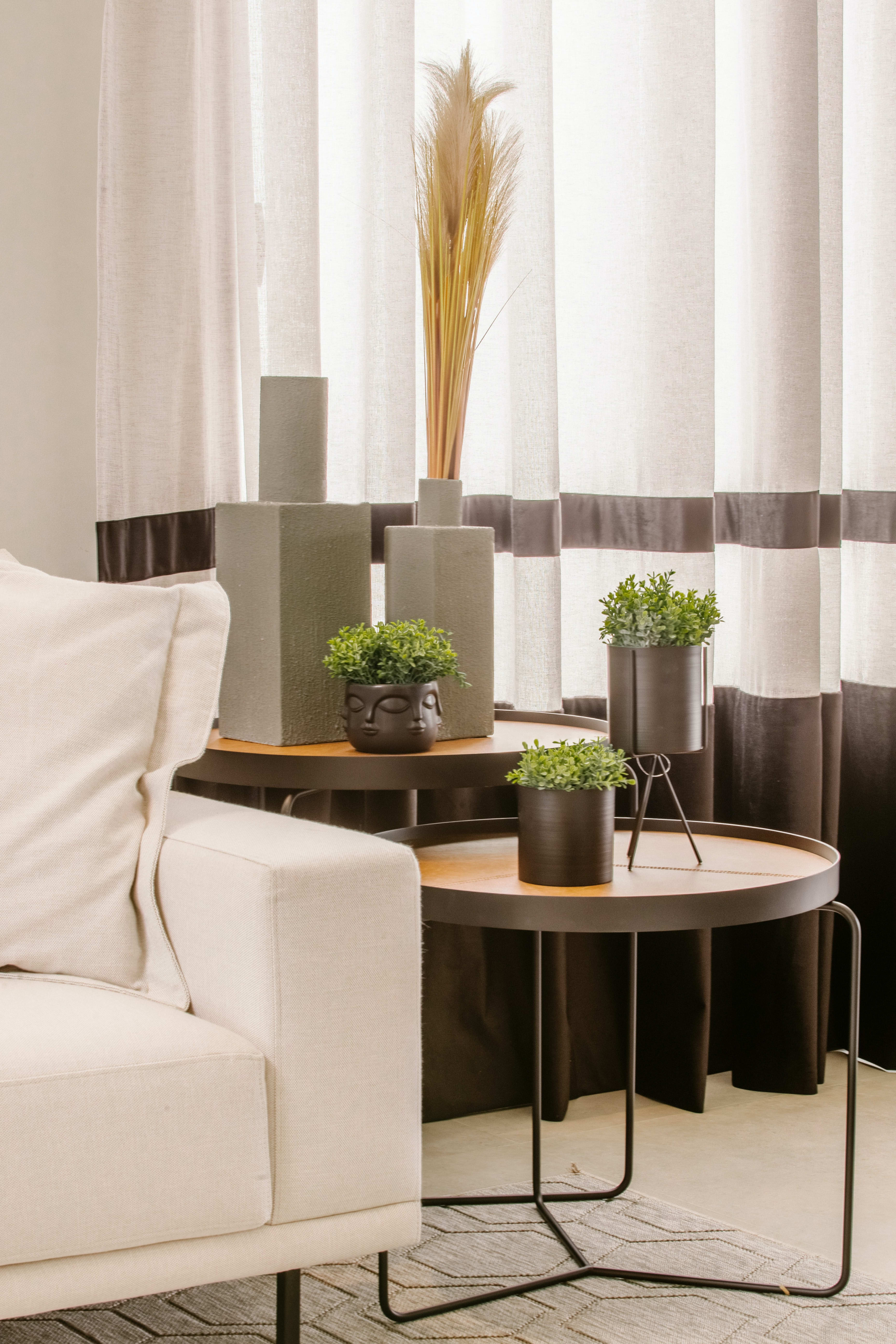 A living room with a white couch, two brown end tables, and vases of green plants