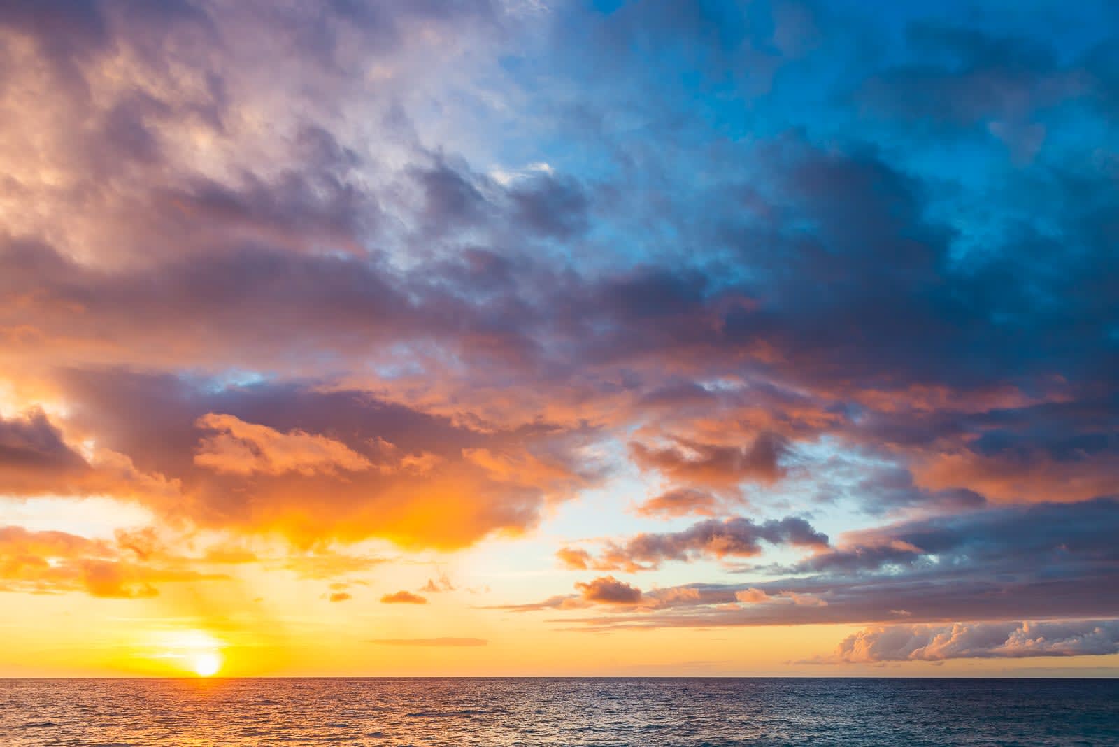 A sunset over the ocean with pink and purple clouds