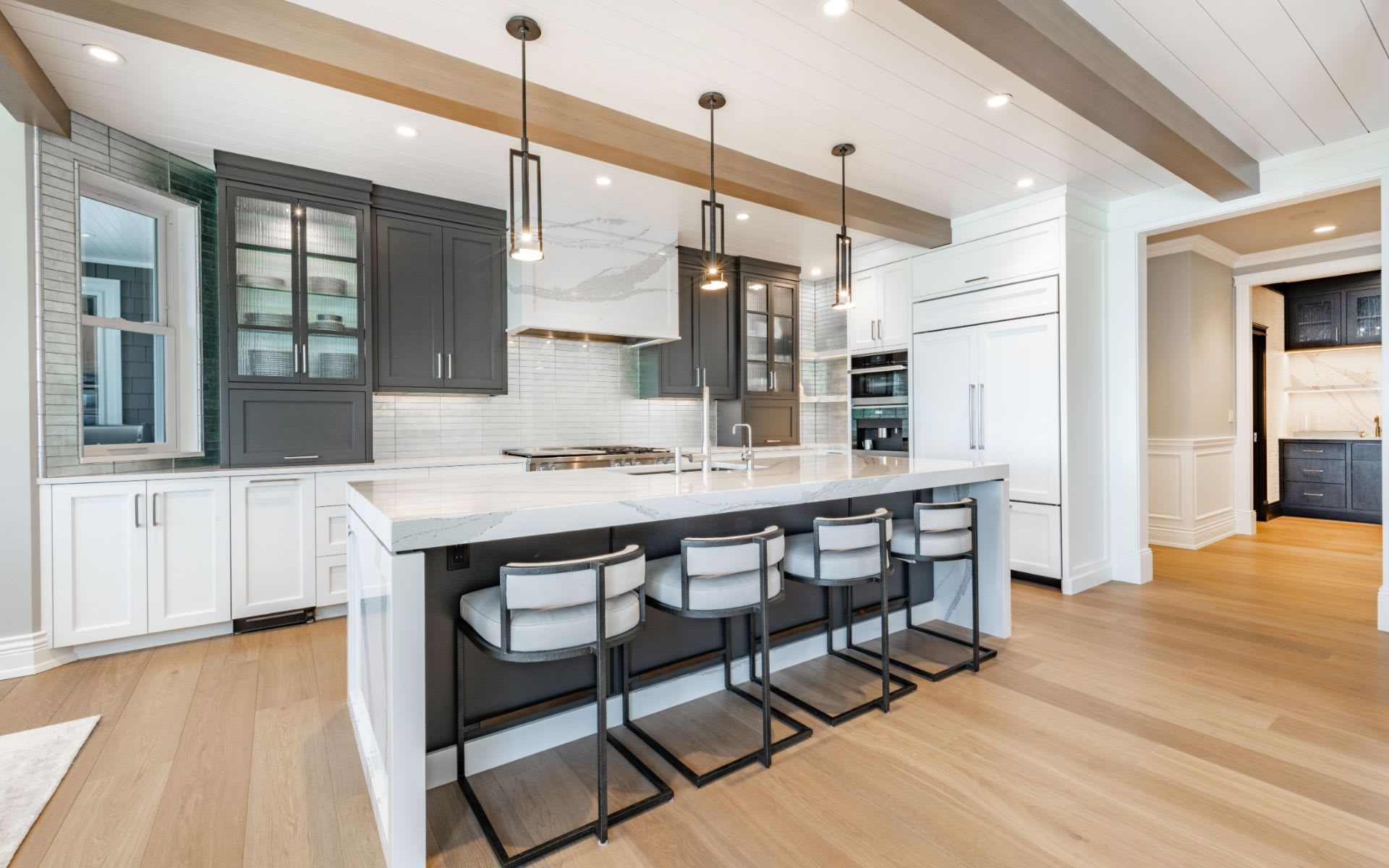 A spacious kitchen with a large central island in white marble, stainless steel appliances, and light-colored cabinets