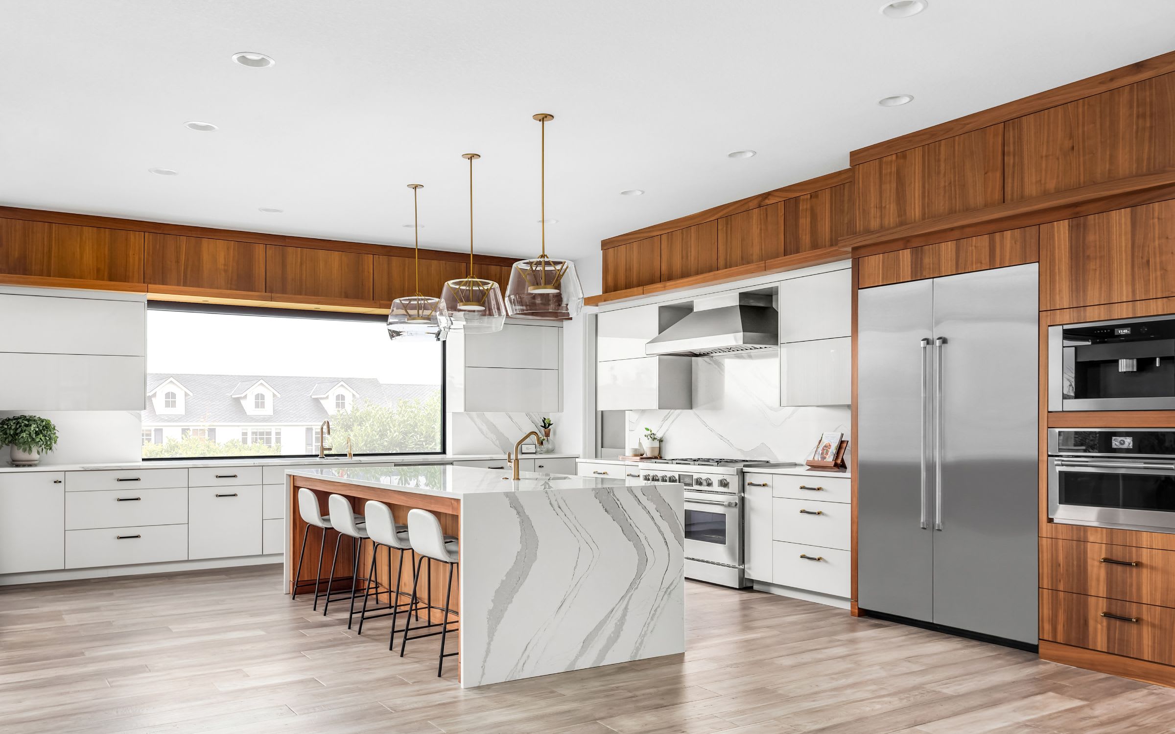 A kitchen with light wood cabinets, stainless steel appliances, and a brown granite countertop.