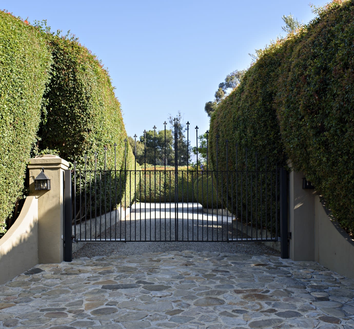 A close-up of a wrought iron gate leading to a driveway. 