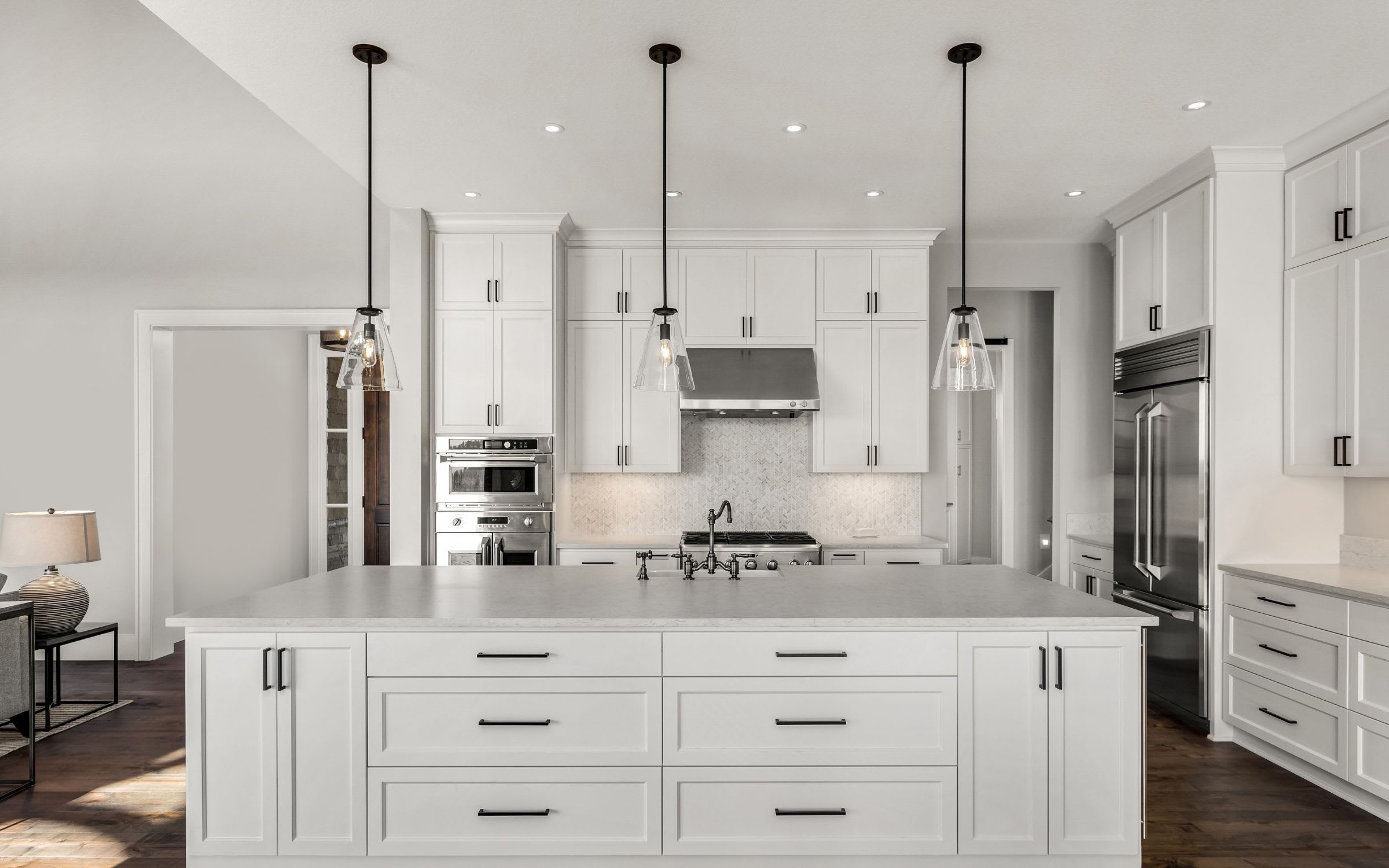 A modern kitchen with white cabinets, stainless steel appliances, and a large island in the center.