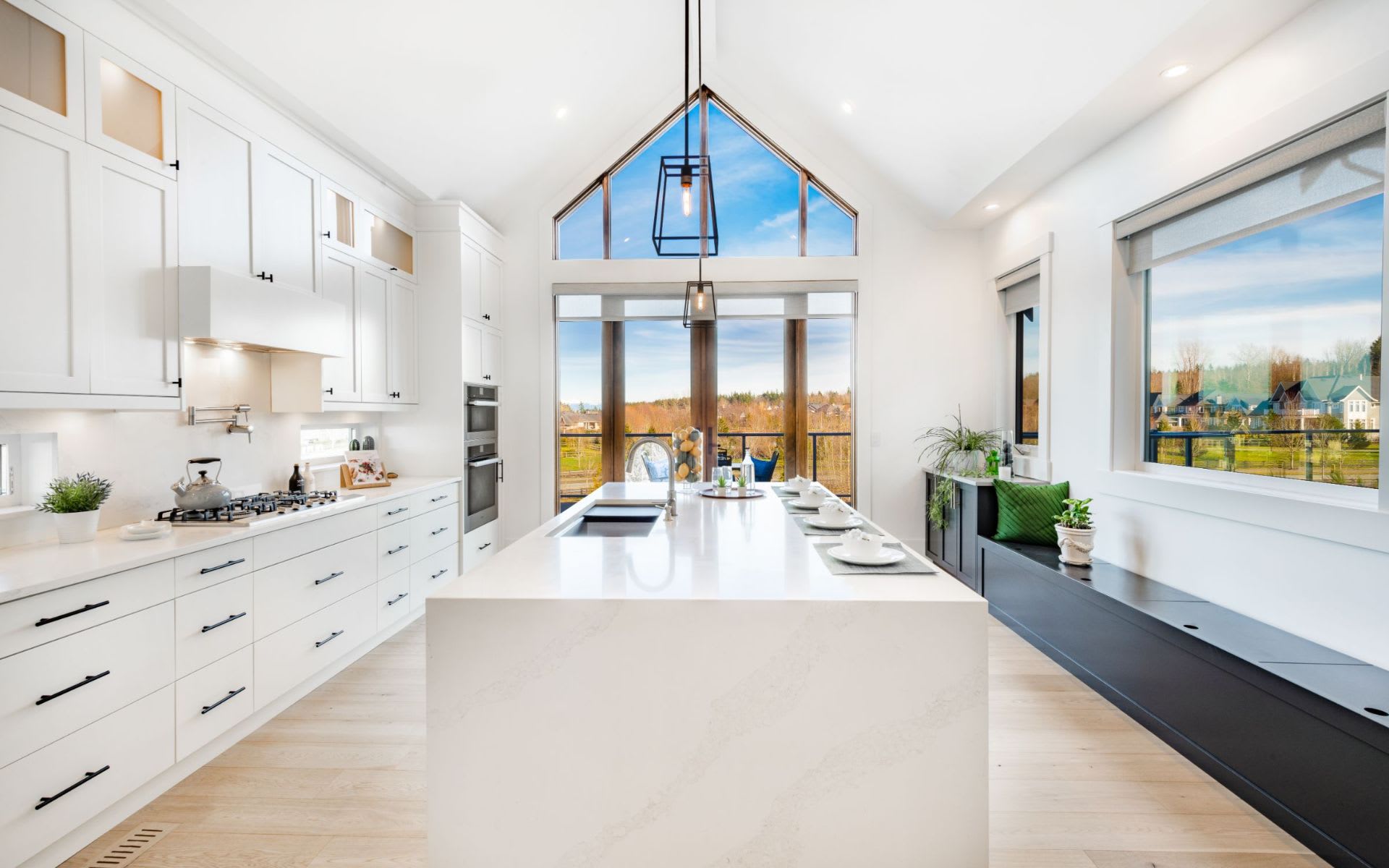 A kitchen with a large island in the center, a sink, a stove, and a window