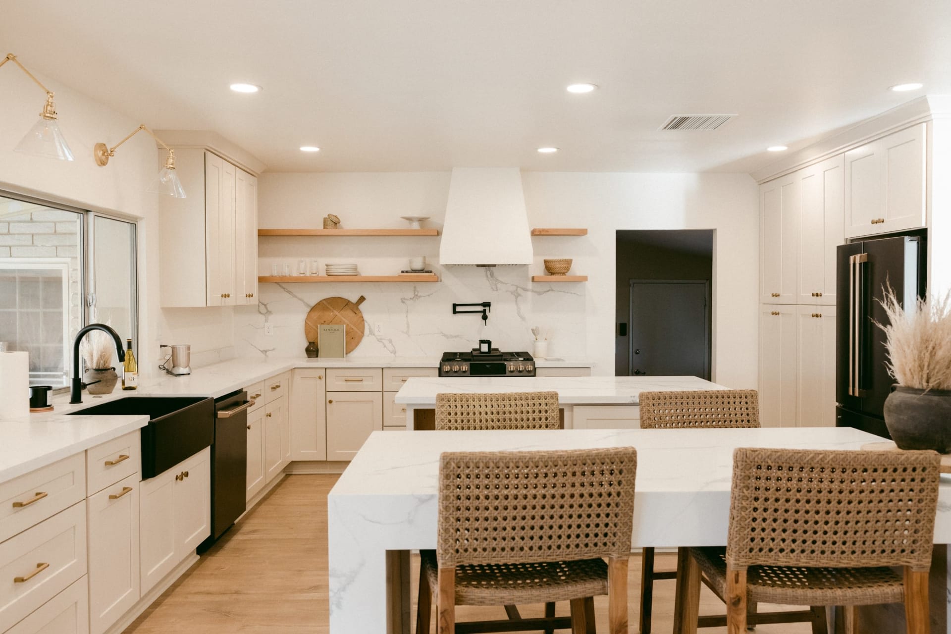 A contemporary kitchen with white cabinets,  stainless steel appliances, garden-view windows, and a dining table and chairs.