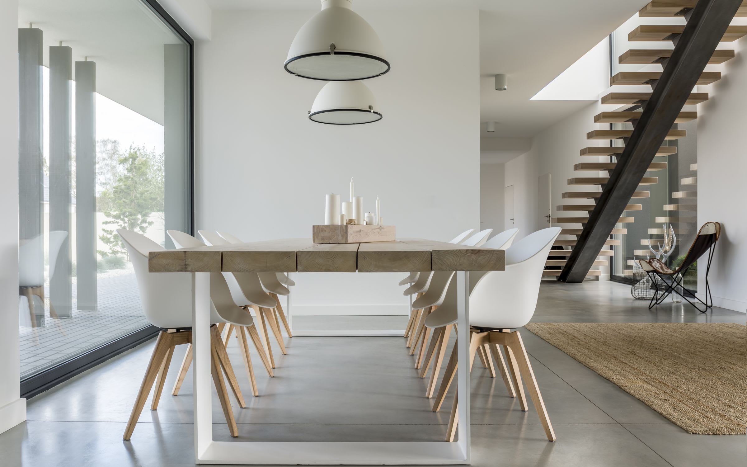 A modern dining room with a large wooden table and white chairs