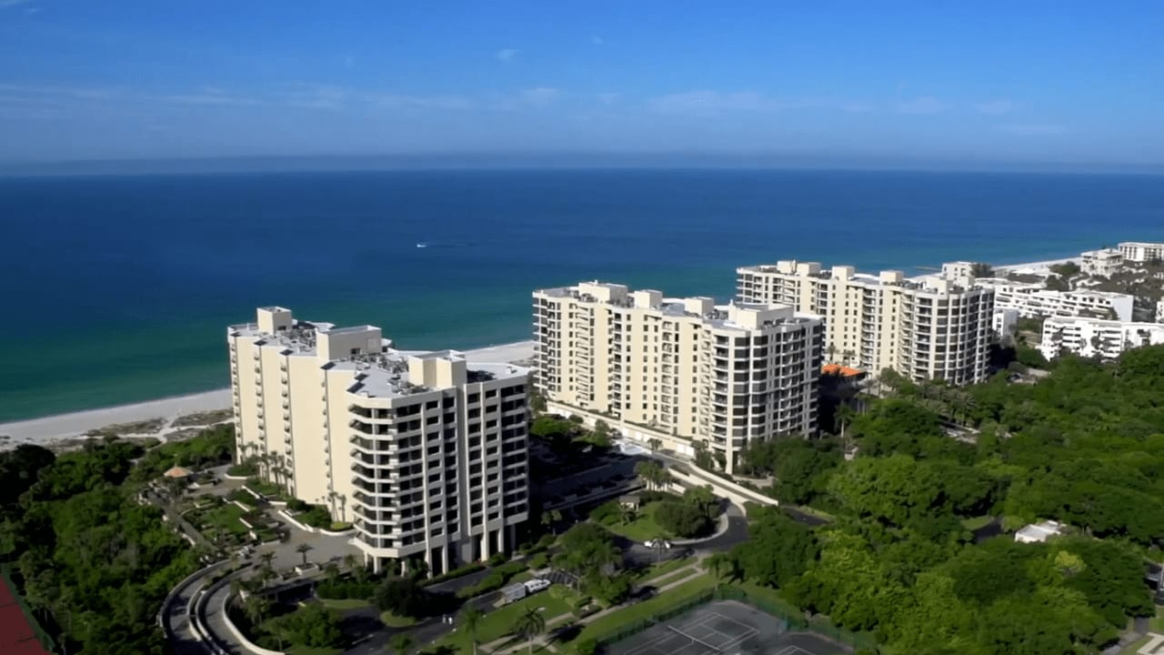 A tropical paradise in Promenade with luxury beachfront buildings, palm trees, and clear blue water