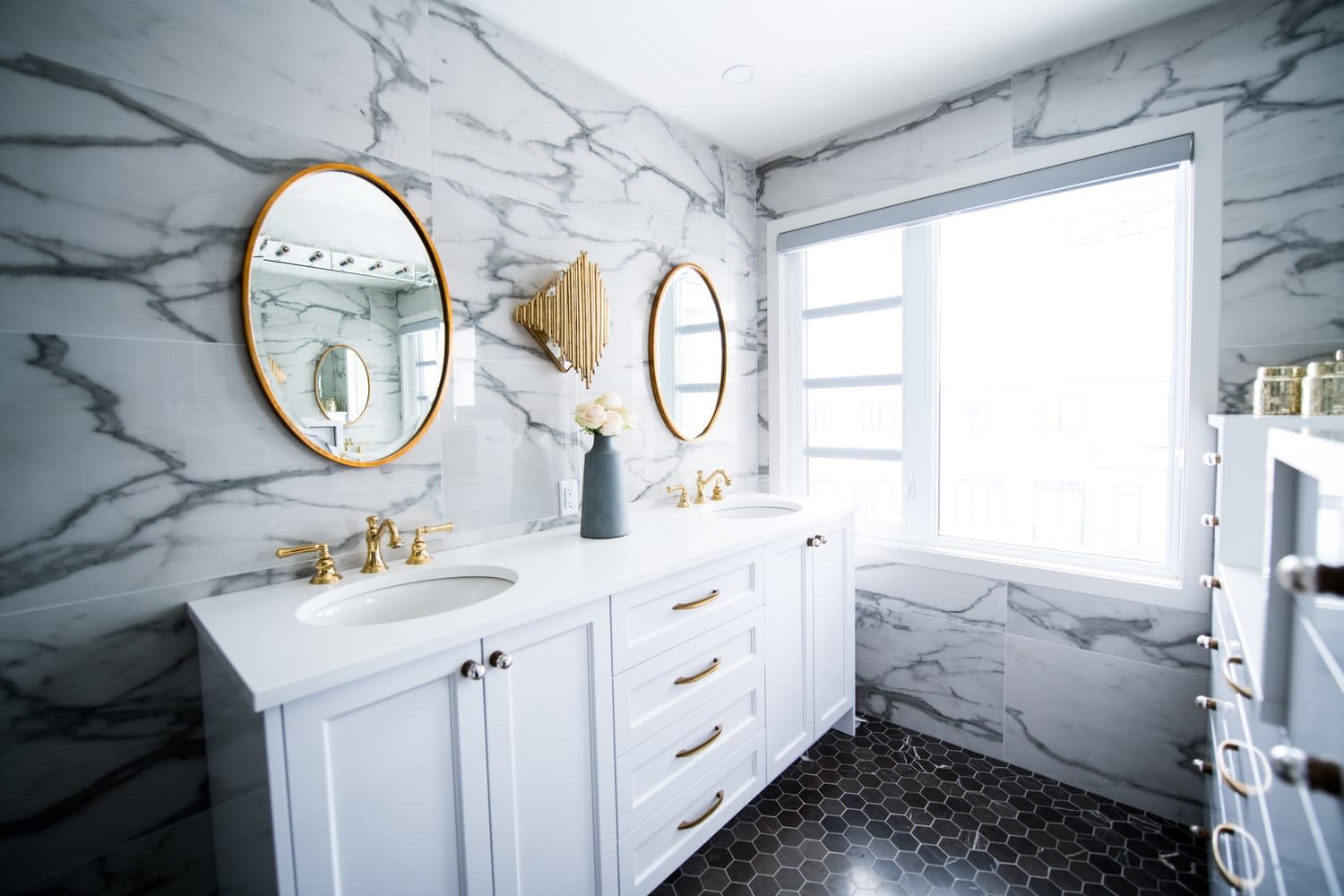 A cozy bathroom with a double vanity, a mirror, and two framed prints above the sinks