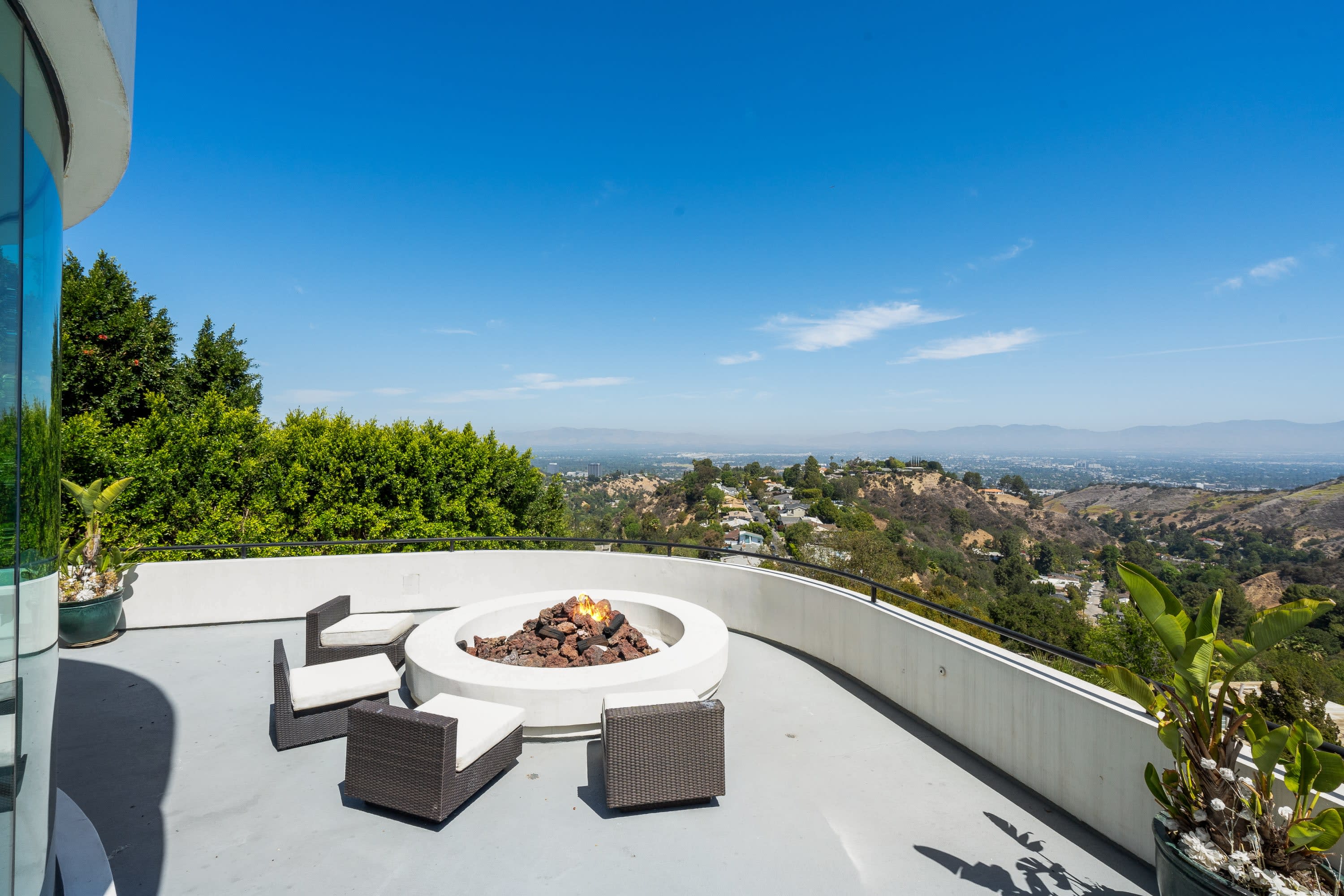 A balcony with a fire pit and chairs overlooking the city