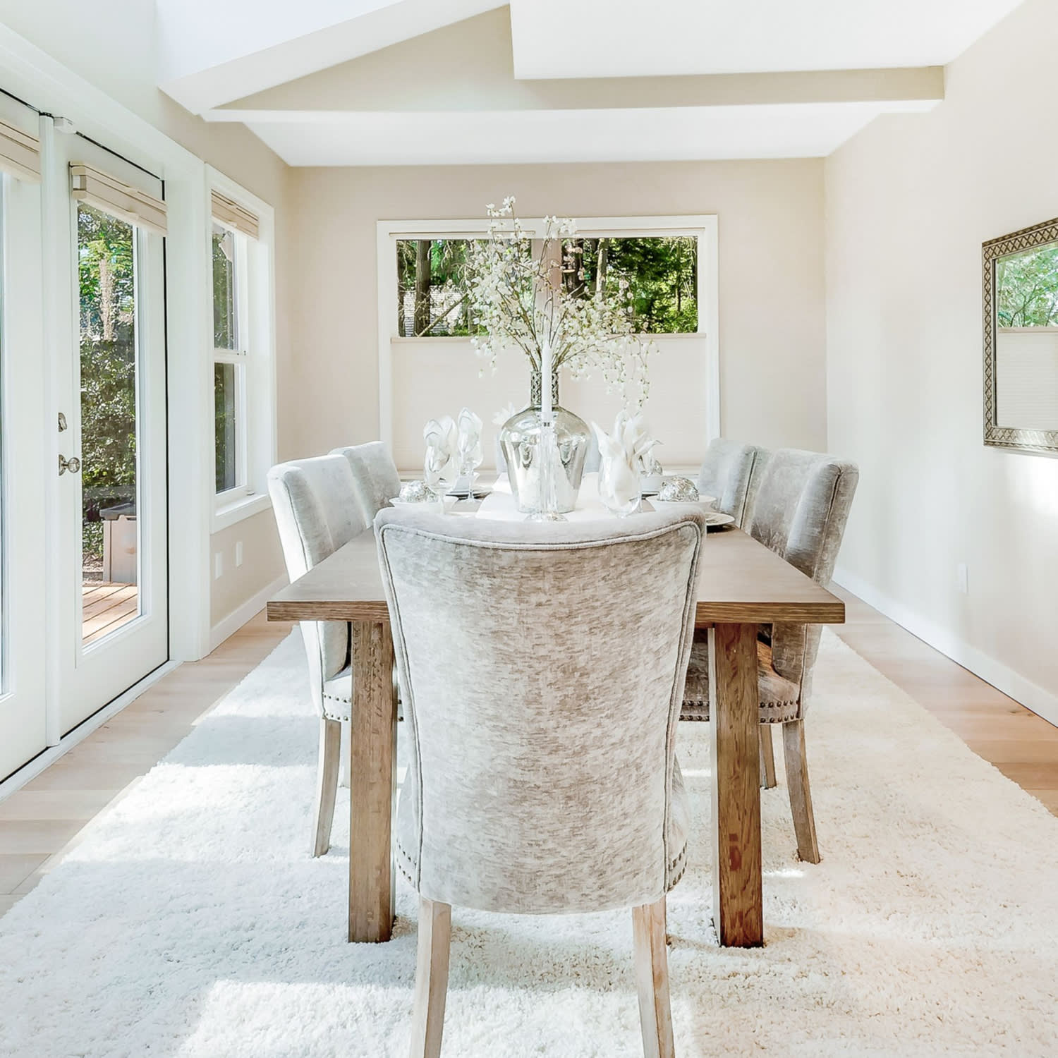 A bright dining room with white walls and a wooden dining table