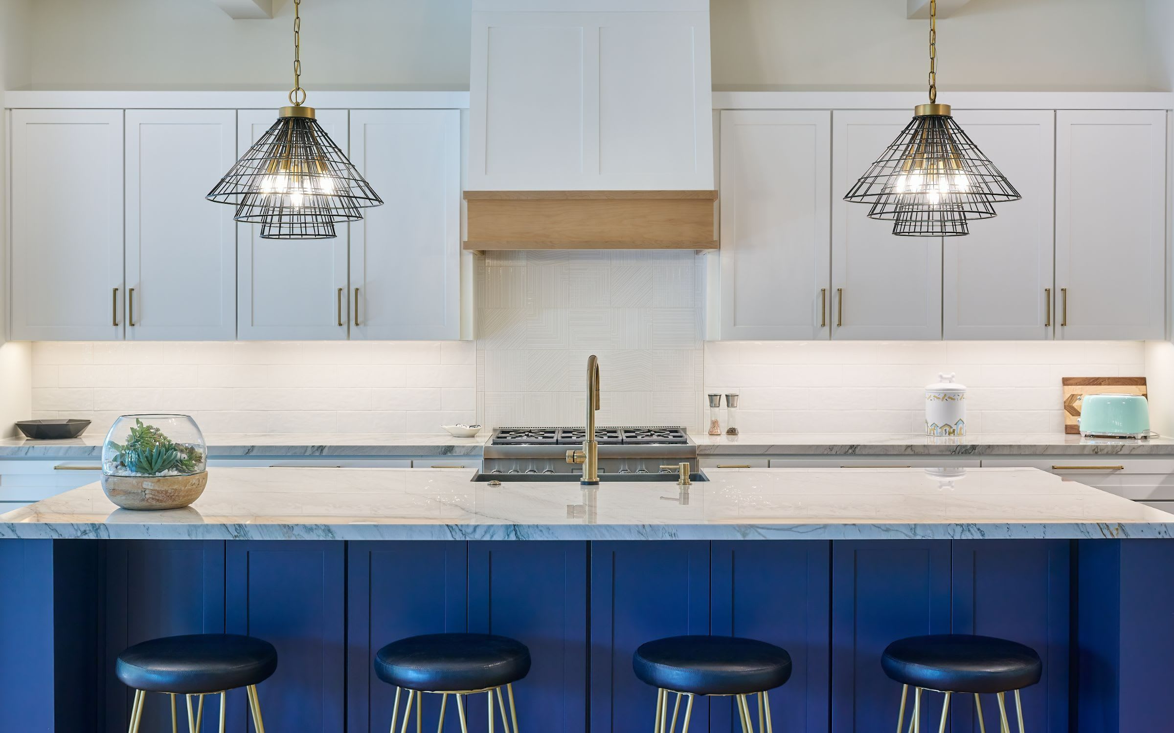 A modern kitchen with blue cabinets and stools.