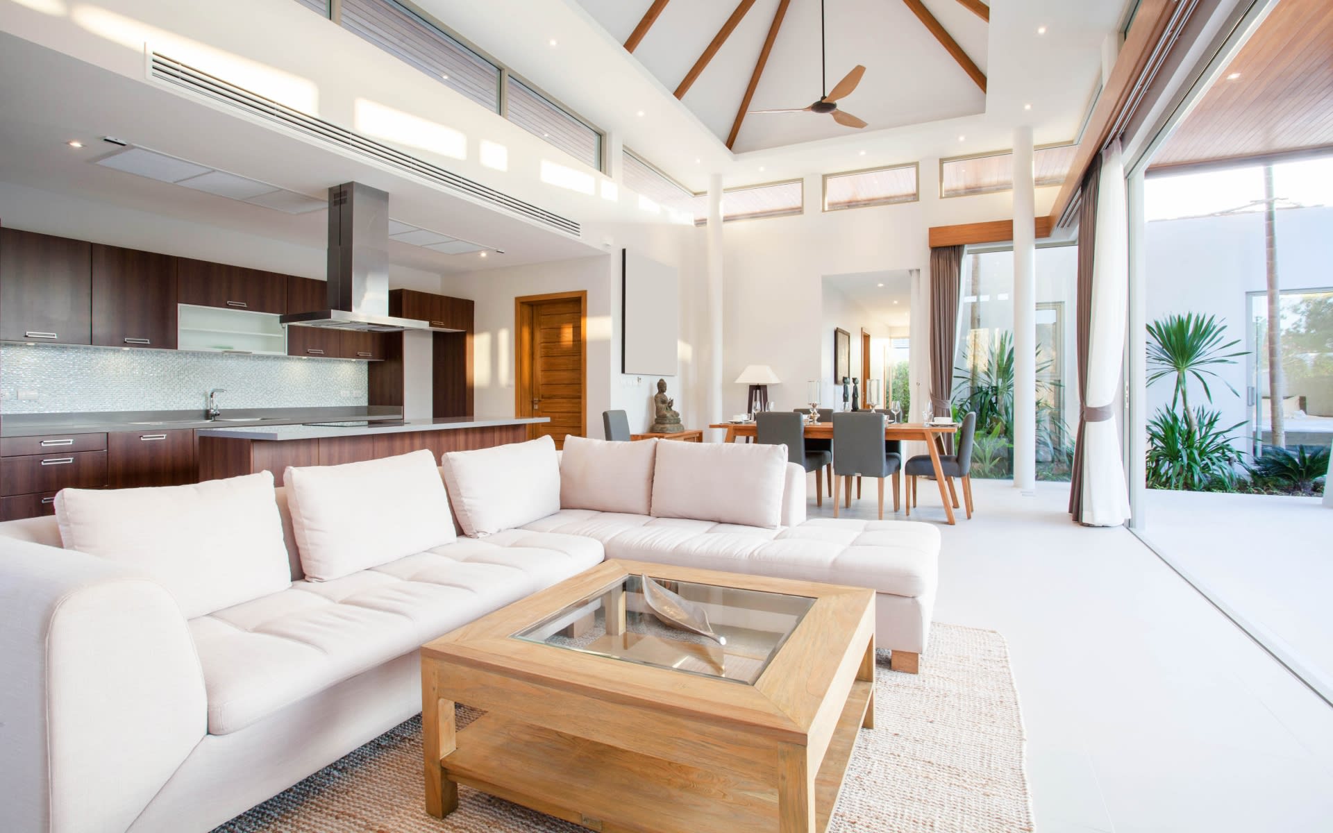 A spacious and modern open-concept living area with a high, vaulted ceiling and wooden beams. 