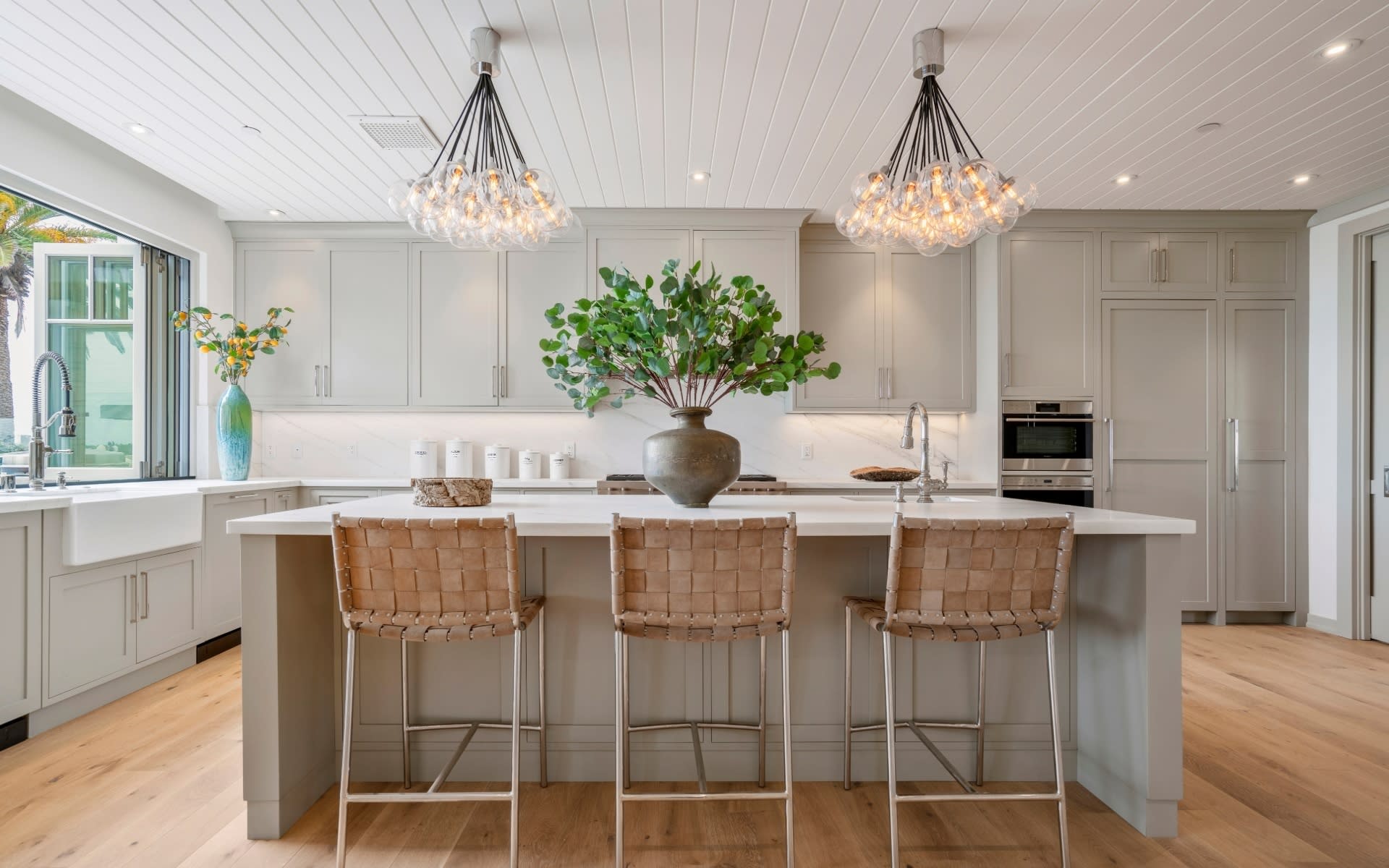 A kitchen with a large center island with bar stools and a vase of flowers on it