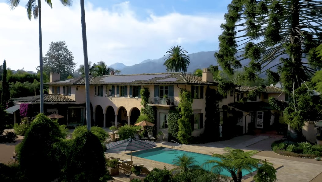 A large mansion with a pool and mountains in the background