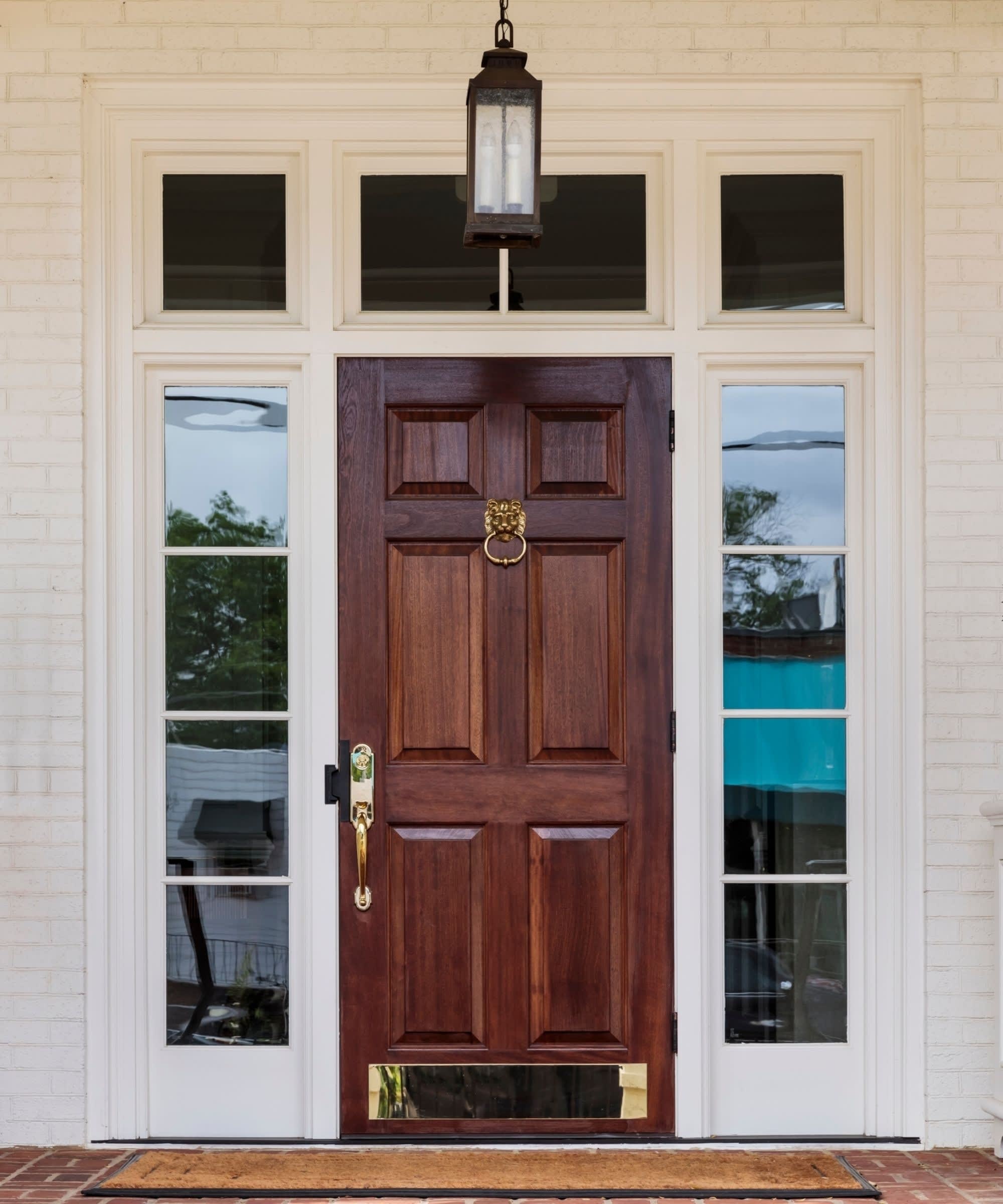 A brown wooden front door with six rectangular glass panes