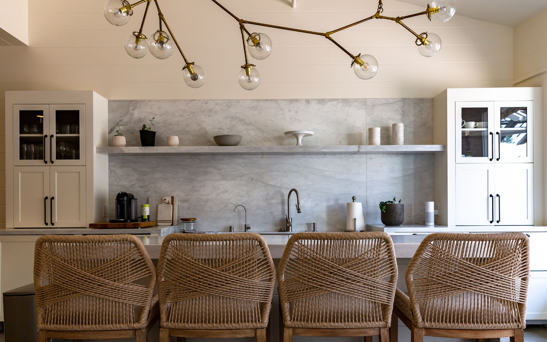 A kitchen island in the center with a sink and faucet, with pendant lights hanging above.