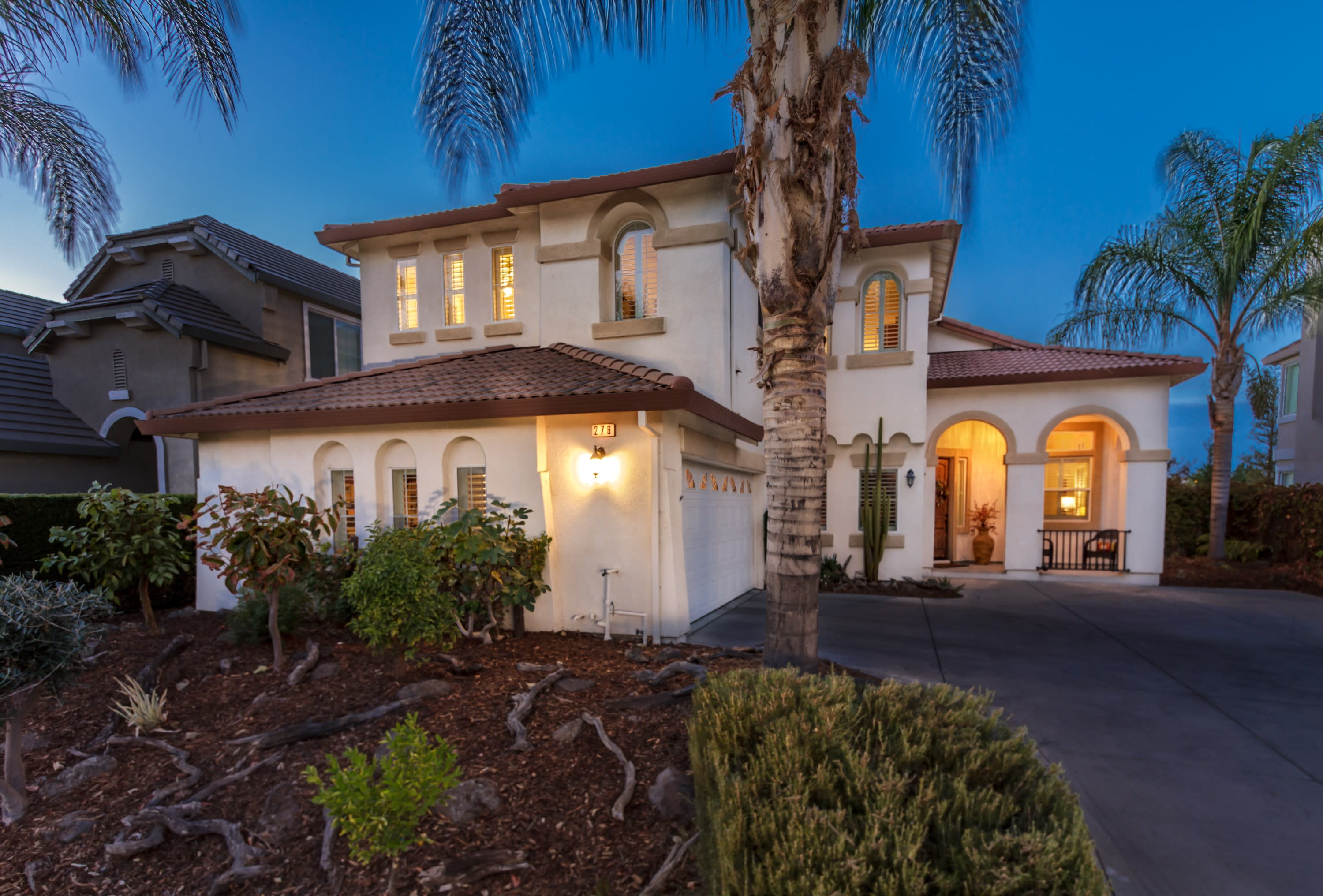 A two-story Mediterranean-style house with a white stucco exterior and a terracotta tile roof