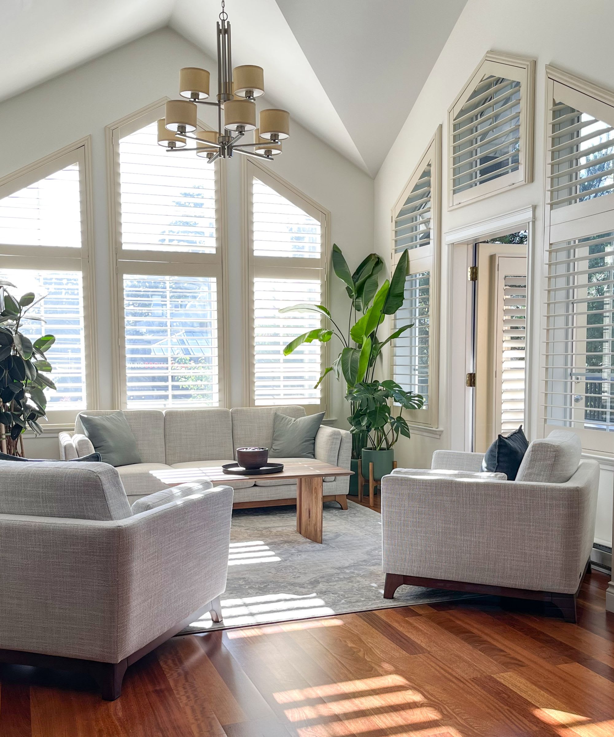 A bright, sunlit living room with vaulted ceilings and large windows