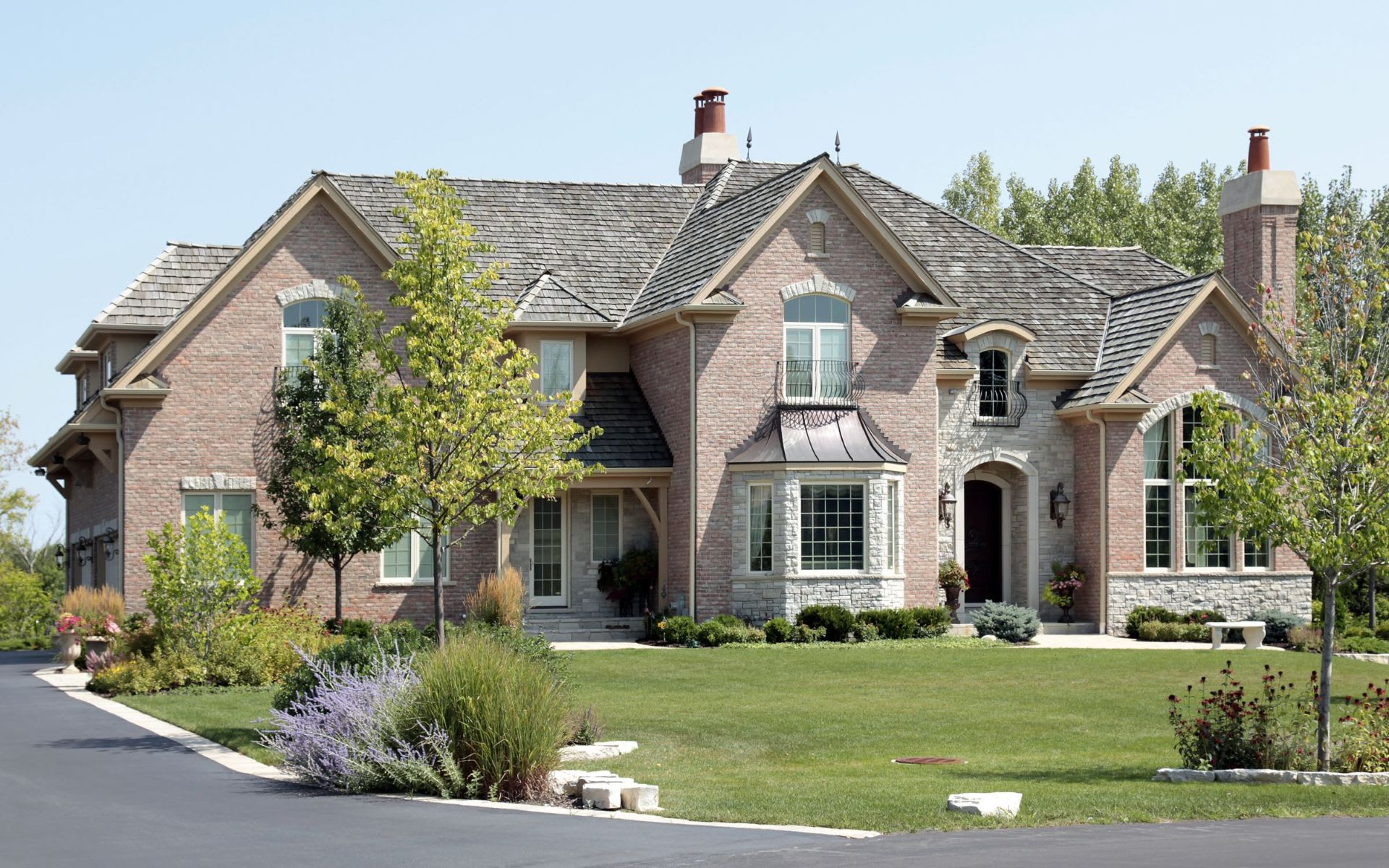 A traditional brick house with a slate roof and a large front yard