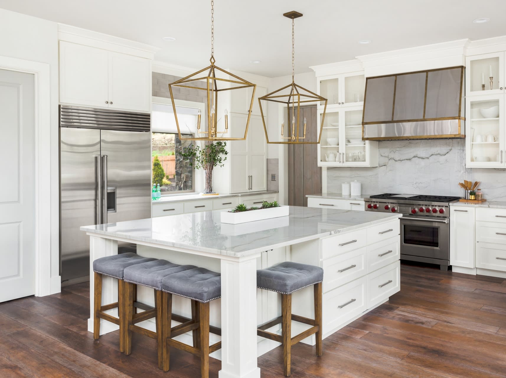 A modern kitchen with a large center island and four stools.