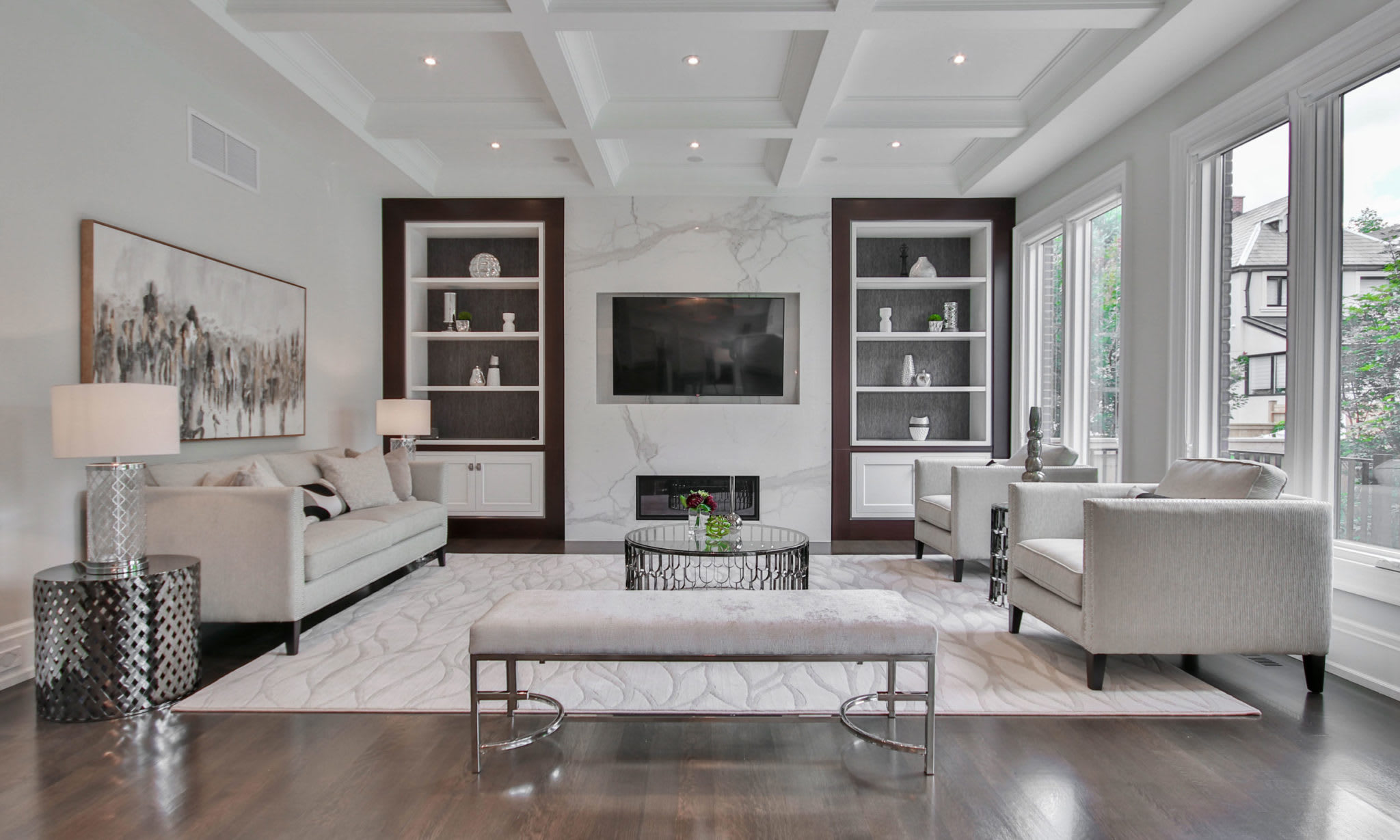 A living room with a couch, chairs, a coffee table, and a flat screen TV mounted on the wall.