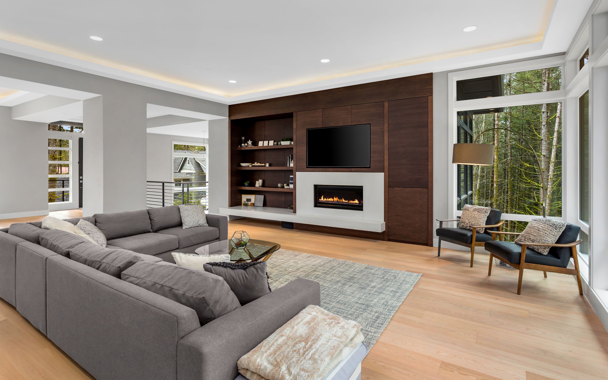 A cozy living room with a plush sectional sofa facing a fireplace and a flat-screen TV.
