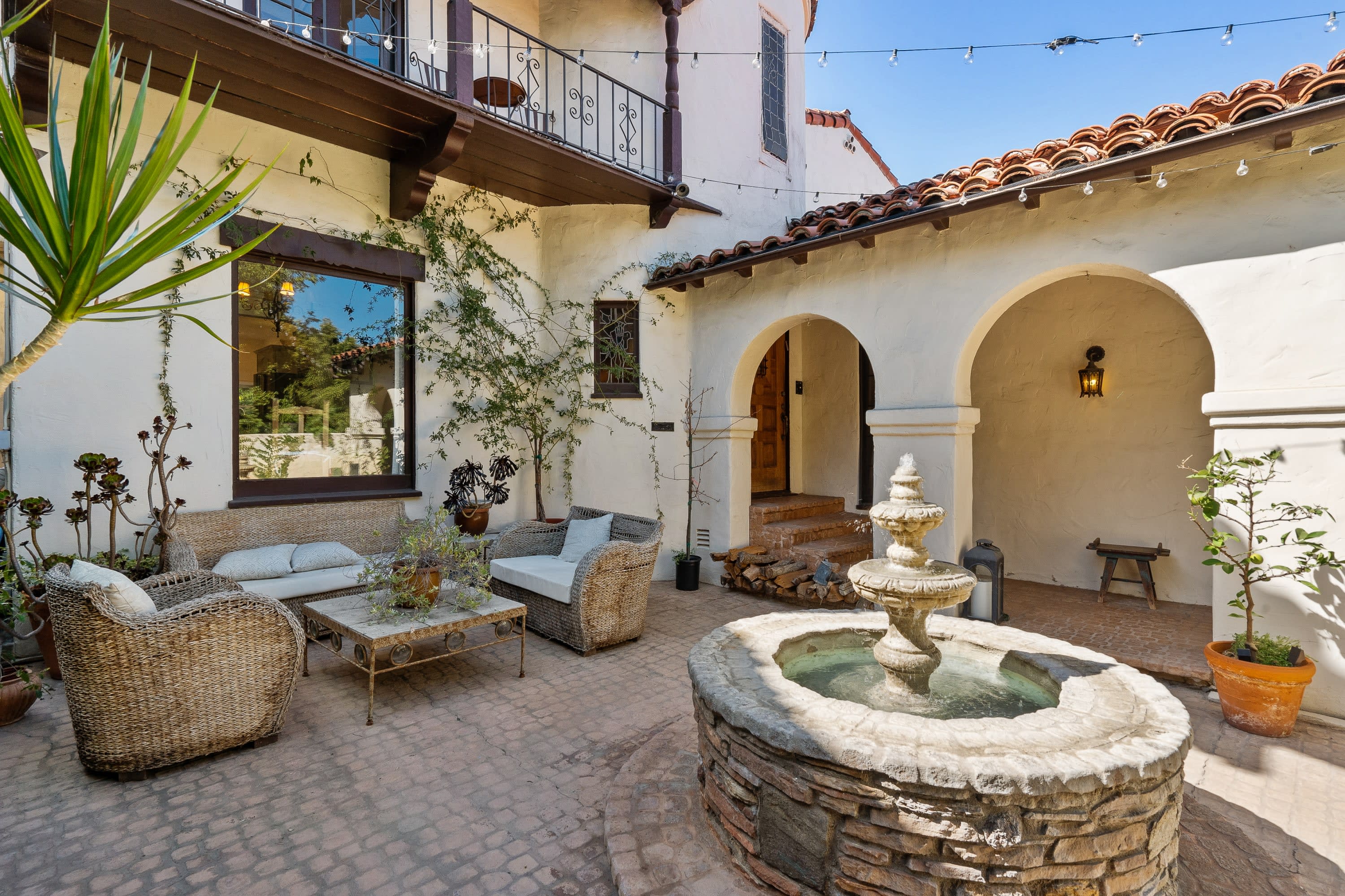 A fountain in the courtyard of a house, surrounded by furniture and greenery