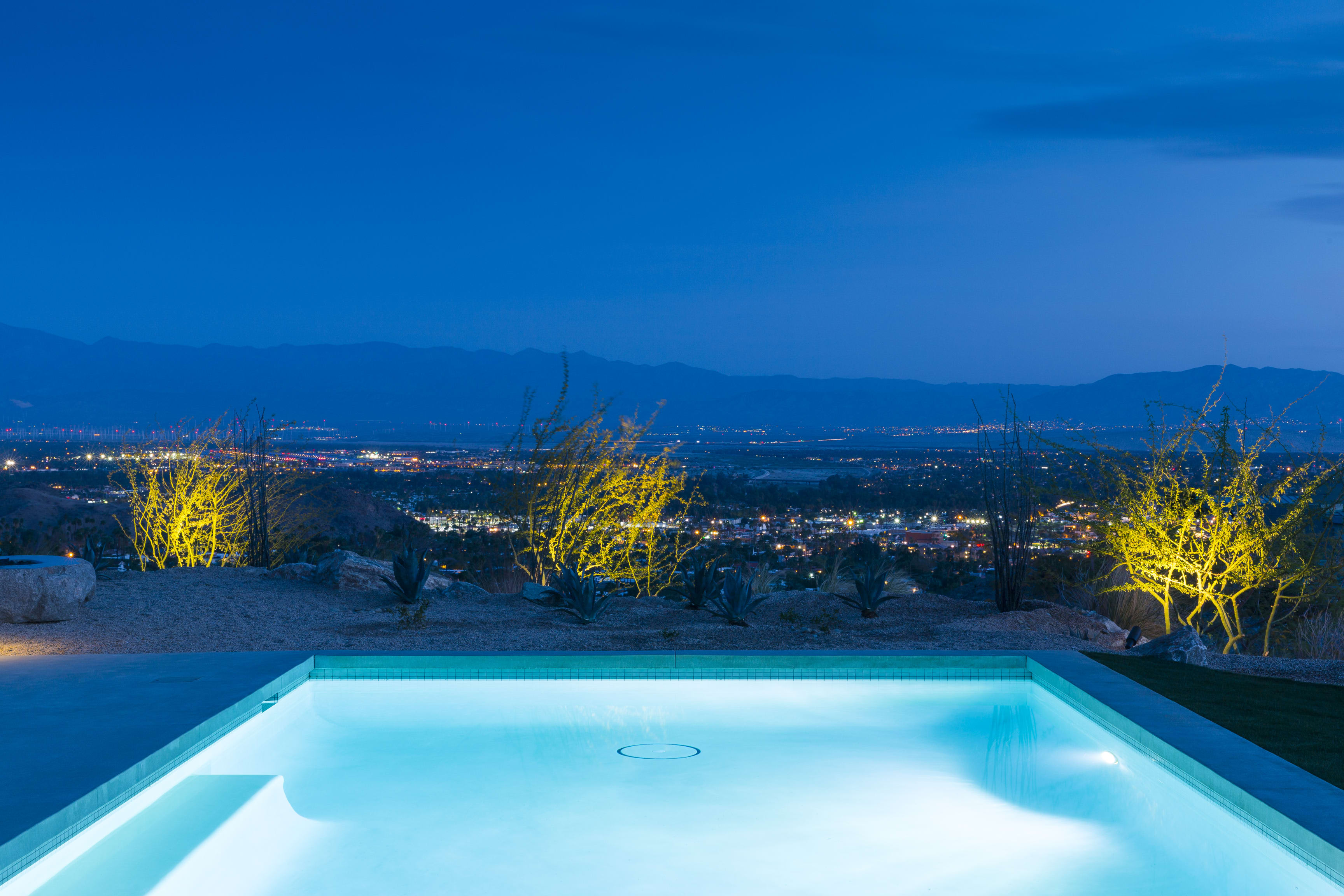 A long, infinity pool stretches out towards the city lights