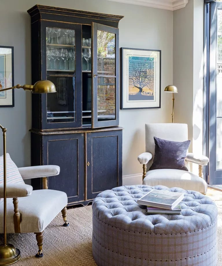 Living room with a distressed navy cabinet and a large round tufted ottoman.