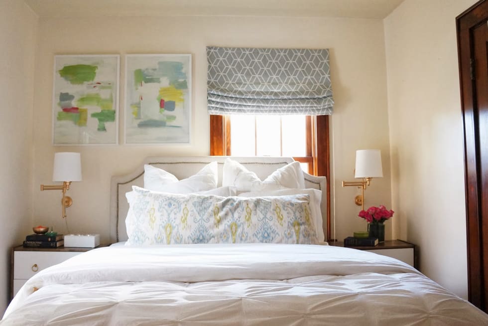 A bed with white lines and fluffy blue-green pillows