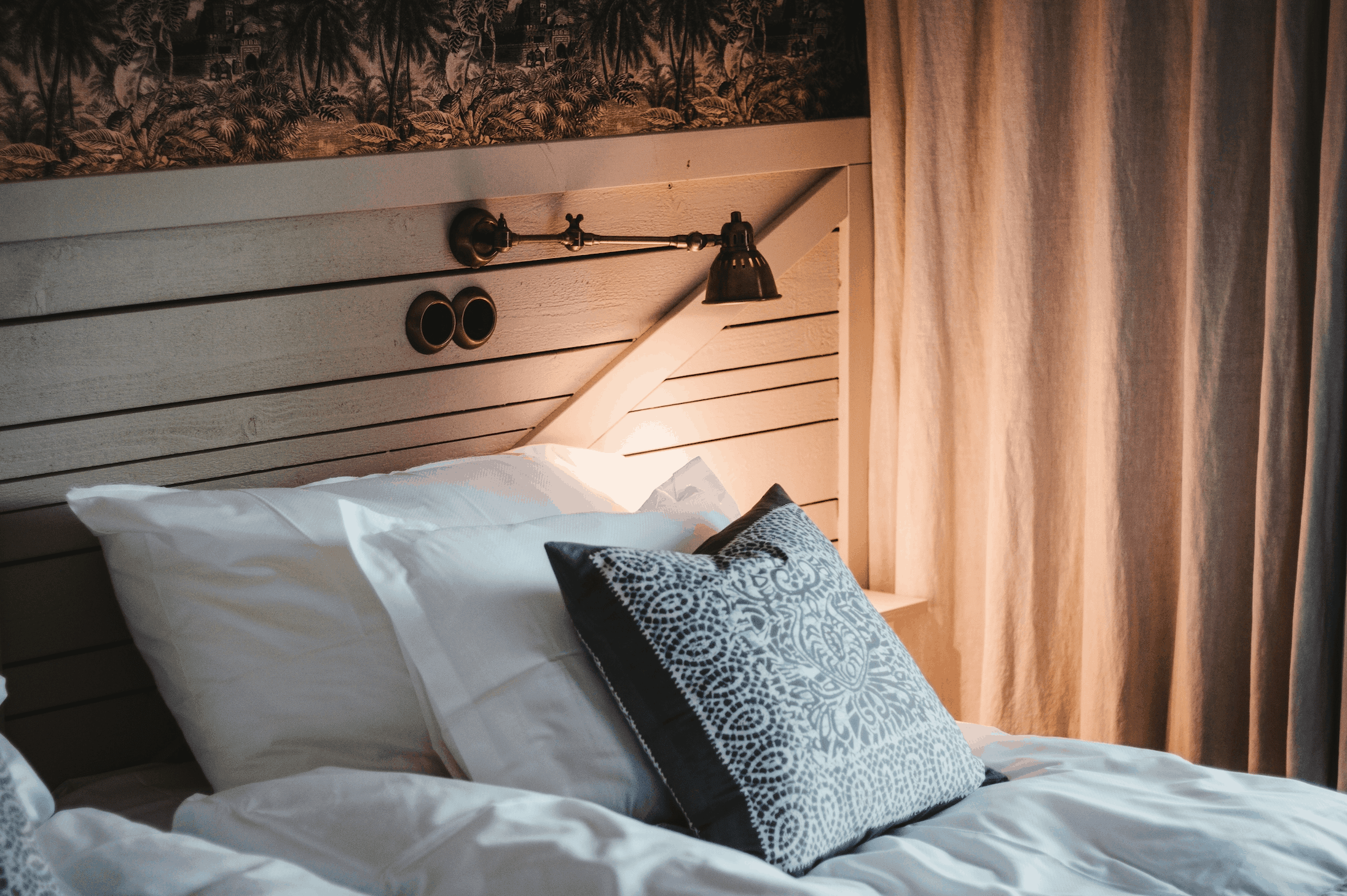 rustic vacation rental bed with decorative pillow on it and a stylish bedside lamp