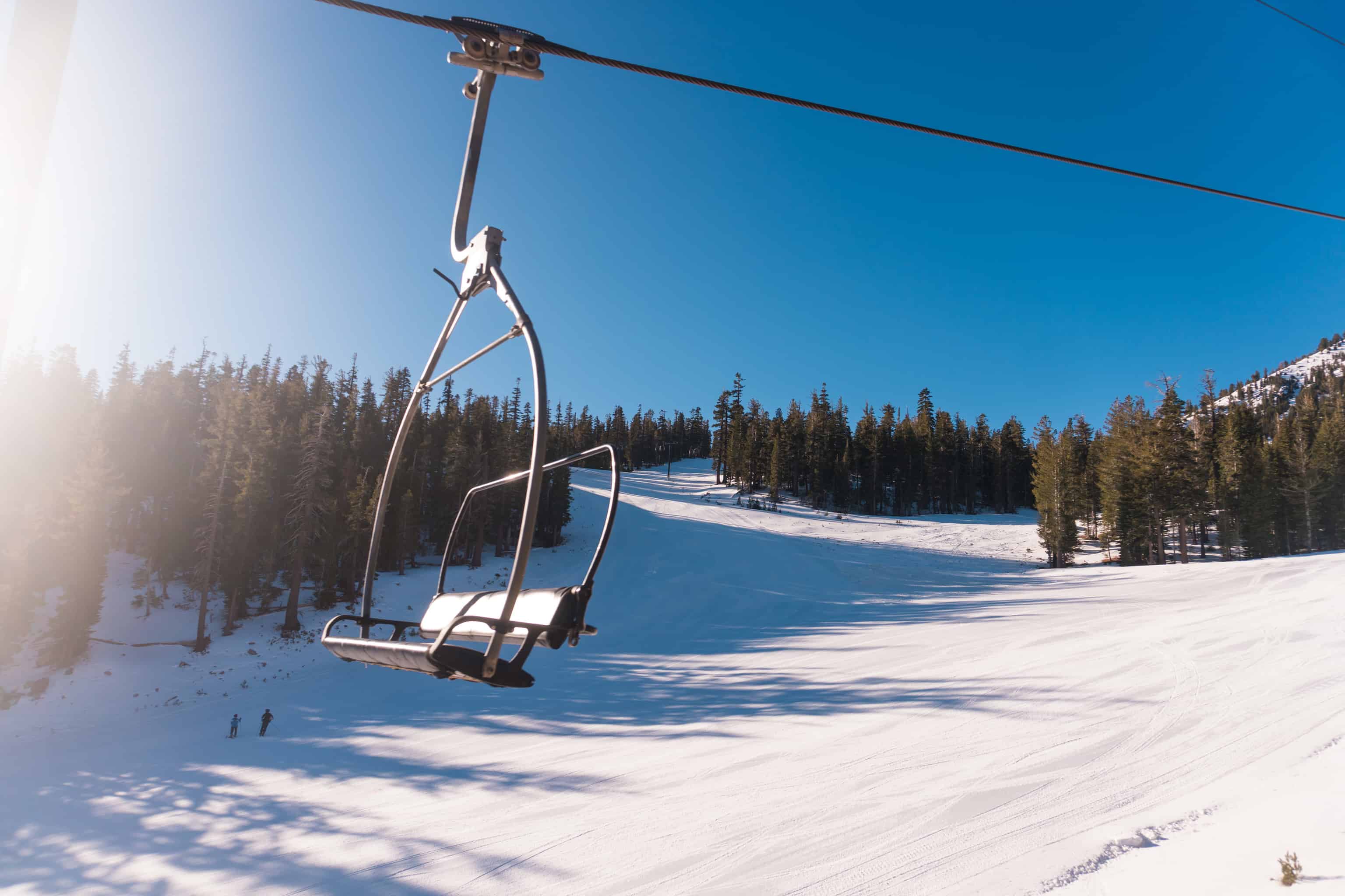 a chairlift catching the afternoon sun on Mammoth Mountain with the ski slope in the background