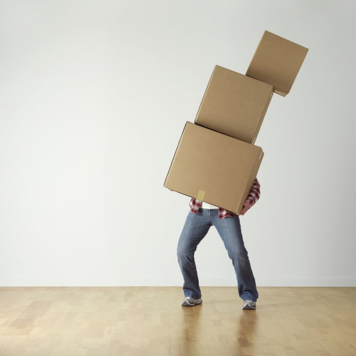 person struggling to carry a leaning tower of boxes