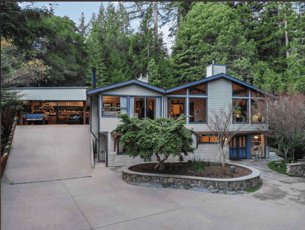 Contemporary two-story home with a wide attached garage, broad driveway, and wooded surroundings.