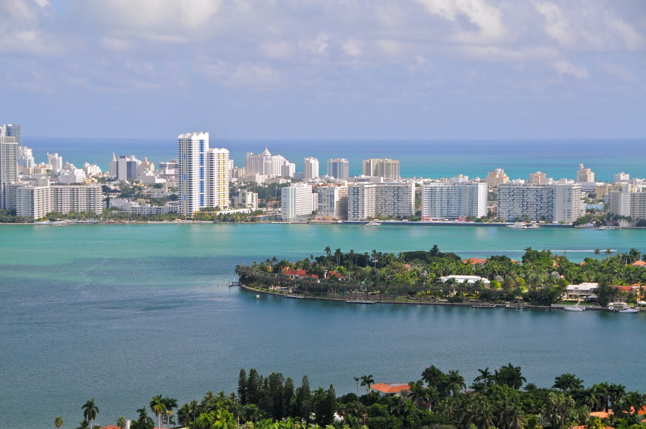 Aerial view of a city with tall buildings and a small island in the middle of the ocean