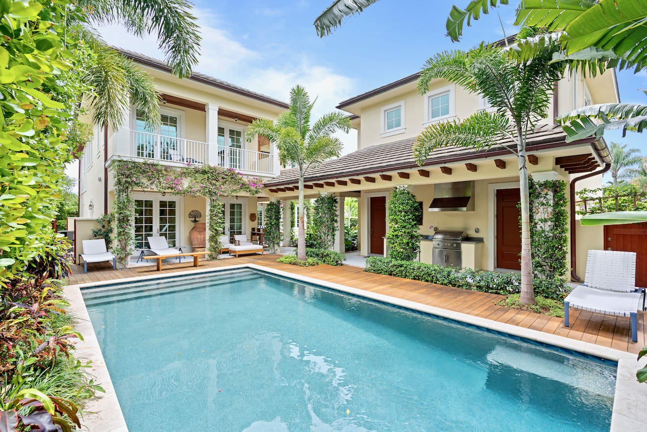 Large Loggia with teak surrounding luxurious blue pool in lush foliage