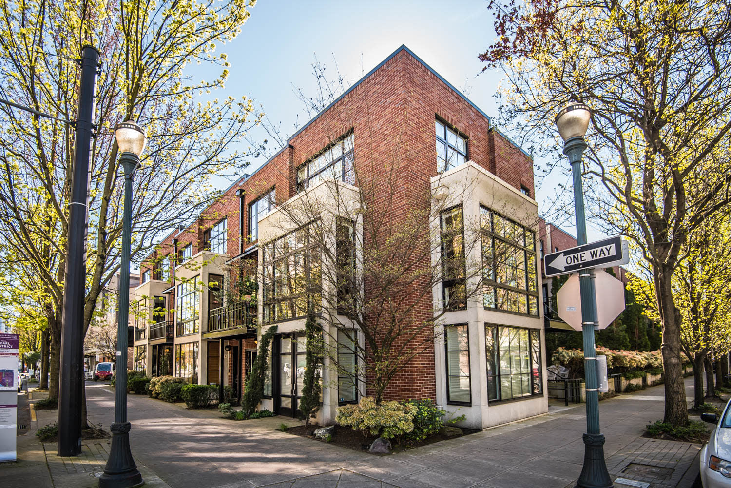 Modern brick townhomes with cream facades and balconies on a tree-lined street.