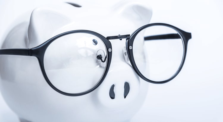 An image of a pair of glasses placed on a piggy bank, suggesting financial advice or savings tips.