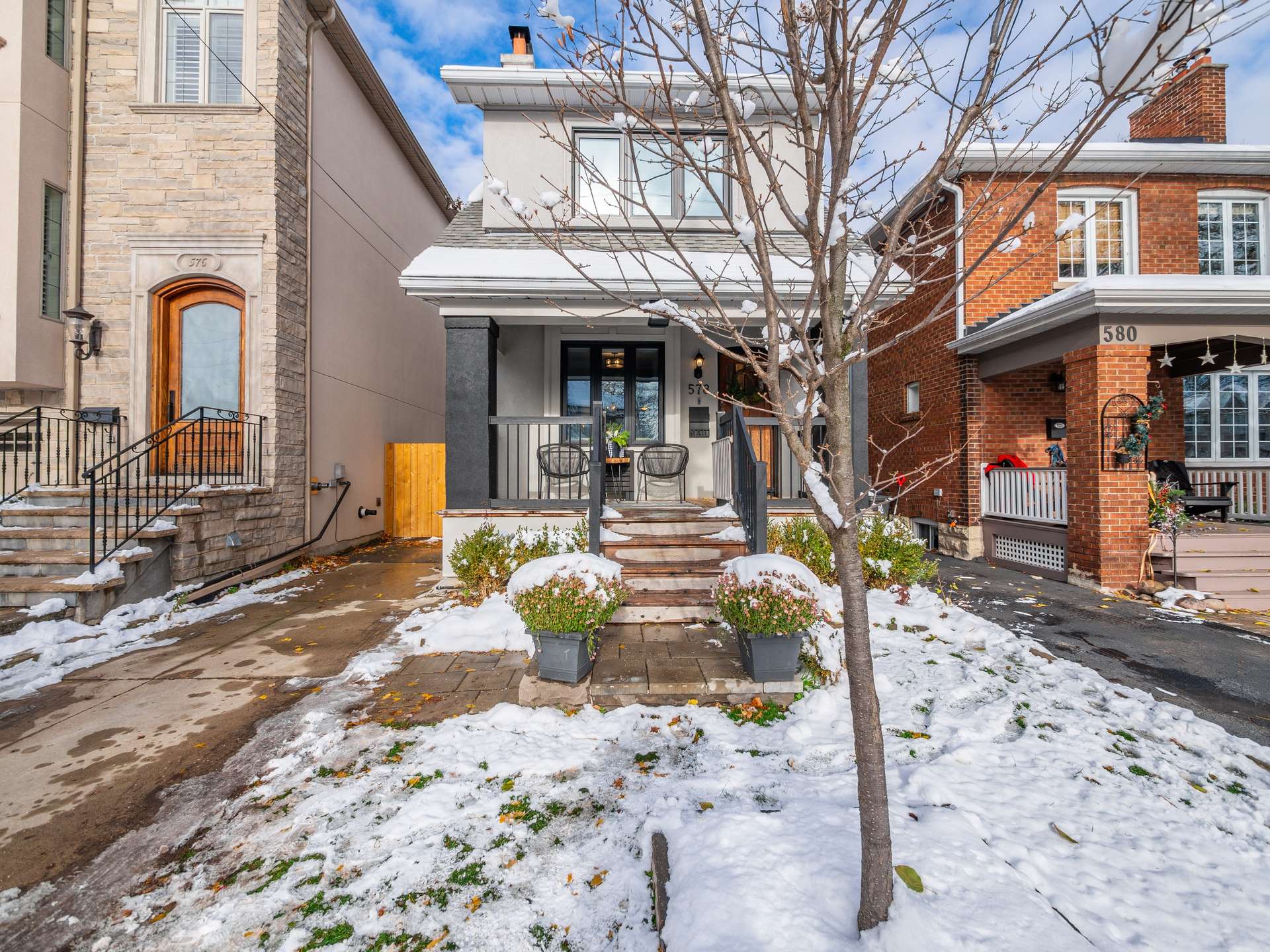 Modern two-story home with a covered porch and snow-covered front yard