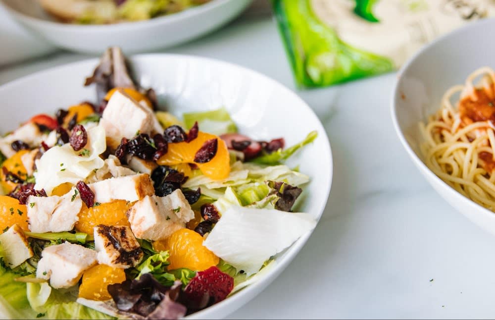 brightly colored grilled chicken salad next to other bowls