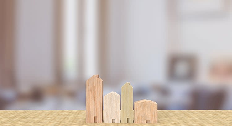 A graphic depicting wooden block models of houses, symbolizing real estate or property momentum.