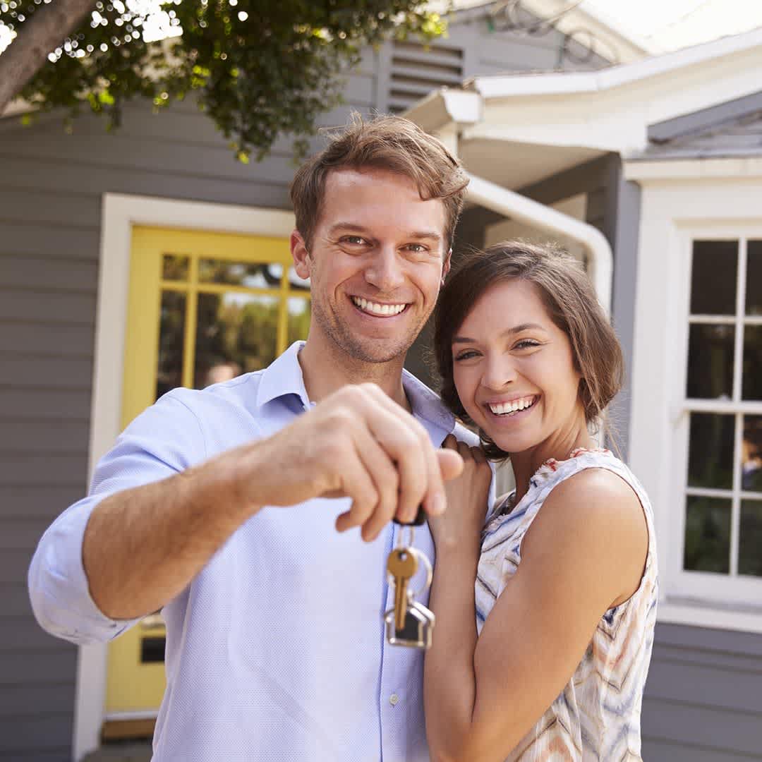 Happy couple holding keys in front of their new home
