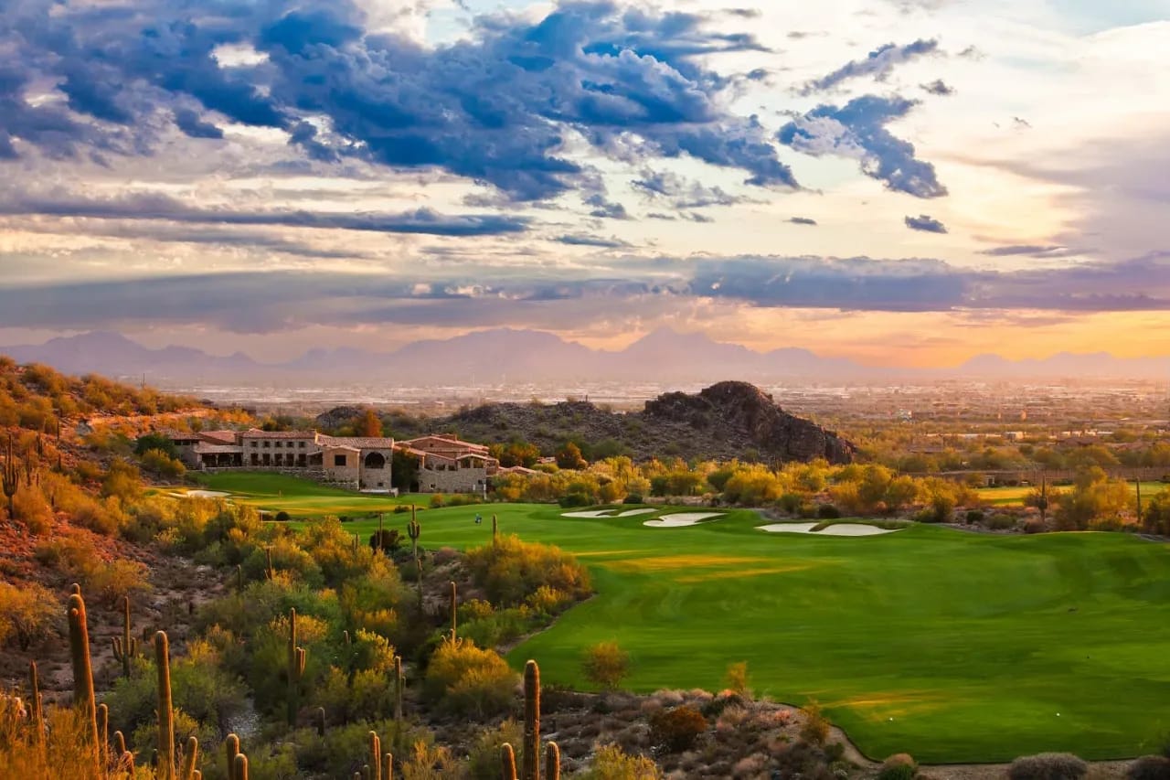 Serene sunset over a world-class golf course, with fairway homes nestled amidst emerald green and golden hues.