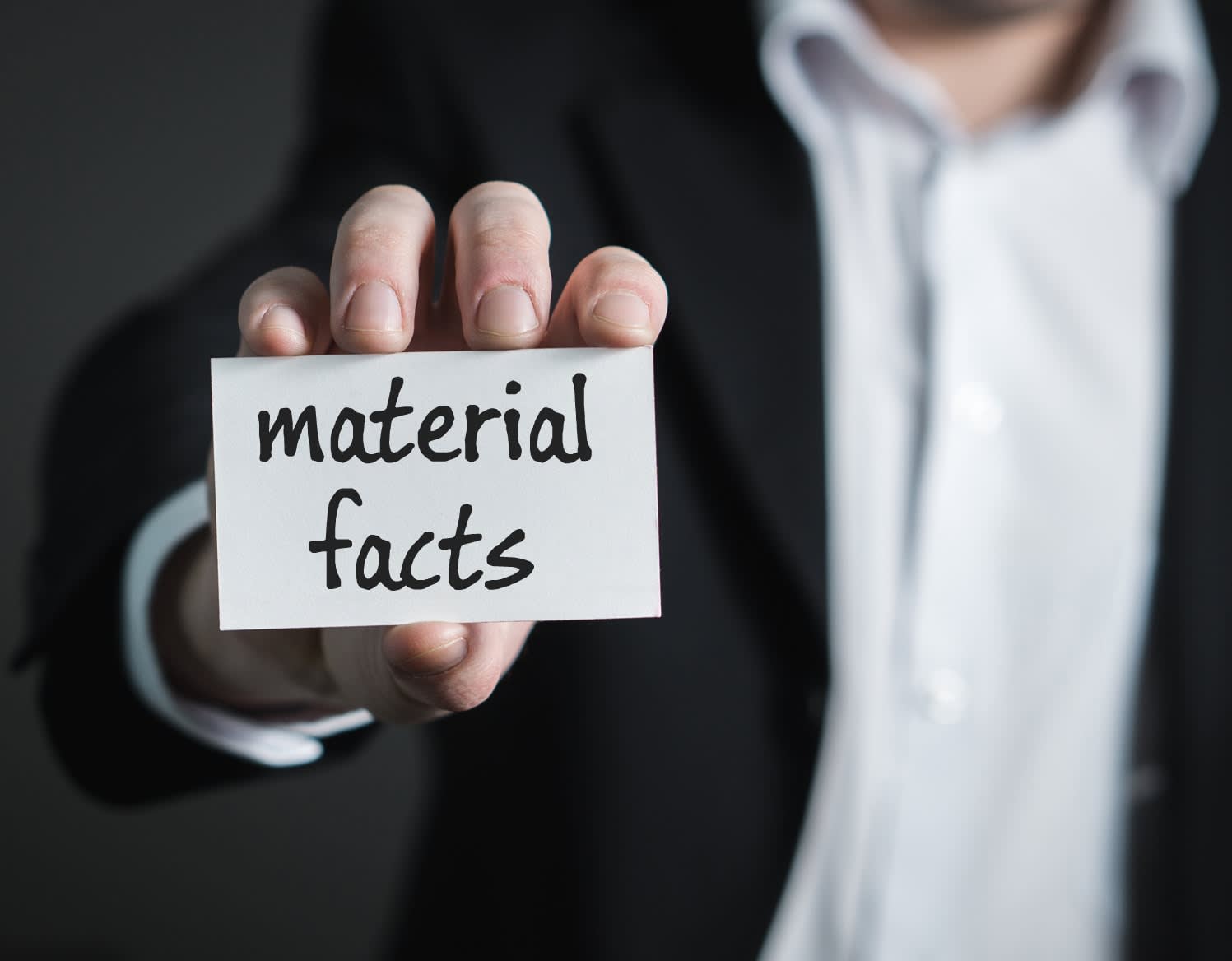 A suited person holds a card labeled “material facts.”