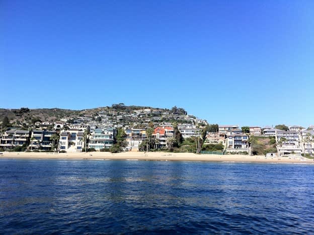 Laguna Beach shoreline with beachfront homes on a hillside overlooking the ocean.